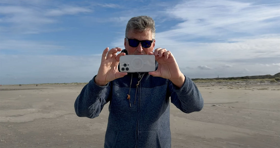 Rainer Wolf filmt mit dem iPhone in der Hand am Strand.