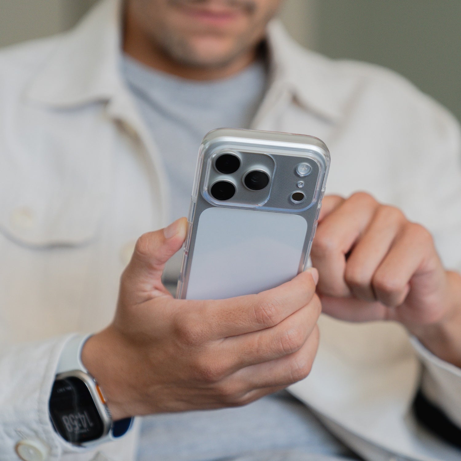 Eine Person, die eine Smartwatch trägt, benutzt ein Smartphone mit dem arktis iPhone 17 Pro Max Invisible Case. Die arktis Hülle bietet sowohl Stil als auch Schutz für den täglichen Gebrauch und lässt das Design des Telefons durchscheinen.