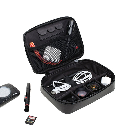 Der MOMENT Wetterfestes Mobile Lens Carrying Case für 4 Linsen in Schwarz fasst Kabel, Objektive, Objektivschutz, ein Ladegerät und wetterfestes Kamerazubehör; einige Gegenstände sind auch außerhalb des Koffers übersichtlich angeordnet.