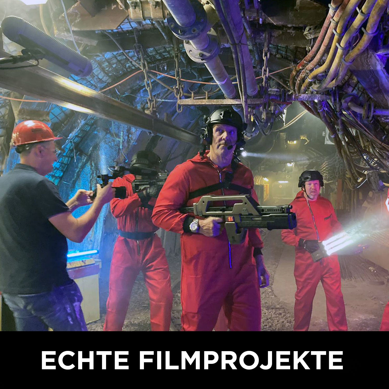 Vier Personen in roten Overalls posieren mit Requisitenwaffen unter blauem und gelbem Licht, während eine weitere Person mit Schutzhelm daneben steht. Text unten: Wolffilms Academy Online-Kurs – Einfach filmen lernen. Marke: Rainer Wolf.