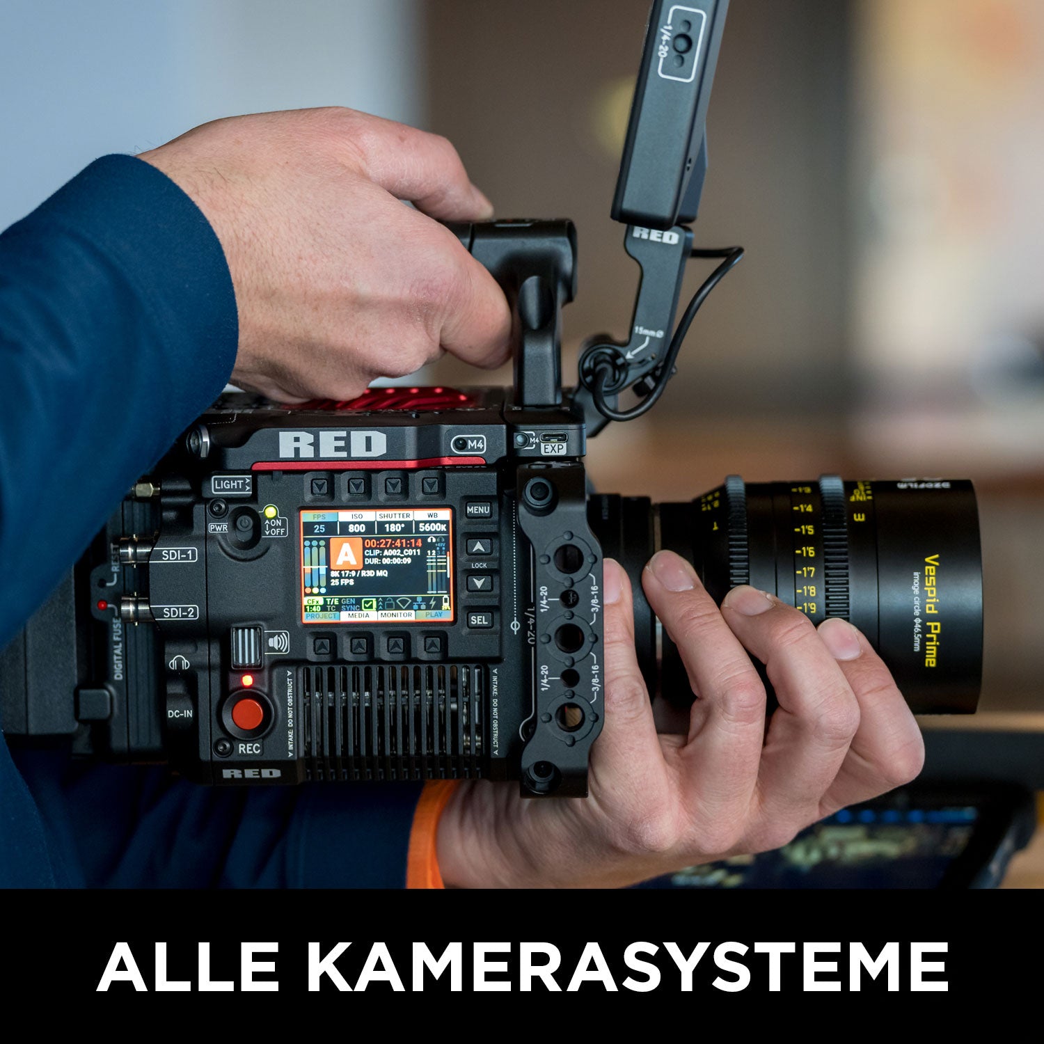 Eine Nahaufnahme zeigt jemanden, der eine RED-Digitalkinokamera mit großem Objektiv und Tasten hält. Text unten: ALLE KAMERASYSTEME – ideal für den Wolffilms Academy Online-Kurs – Einfach filmen lernen von Rainer Wolf.