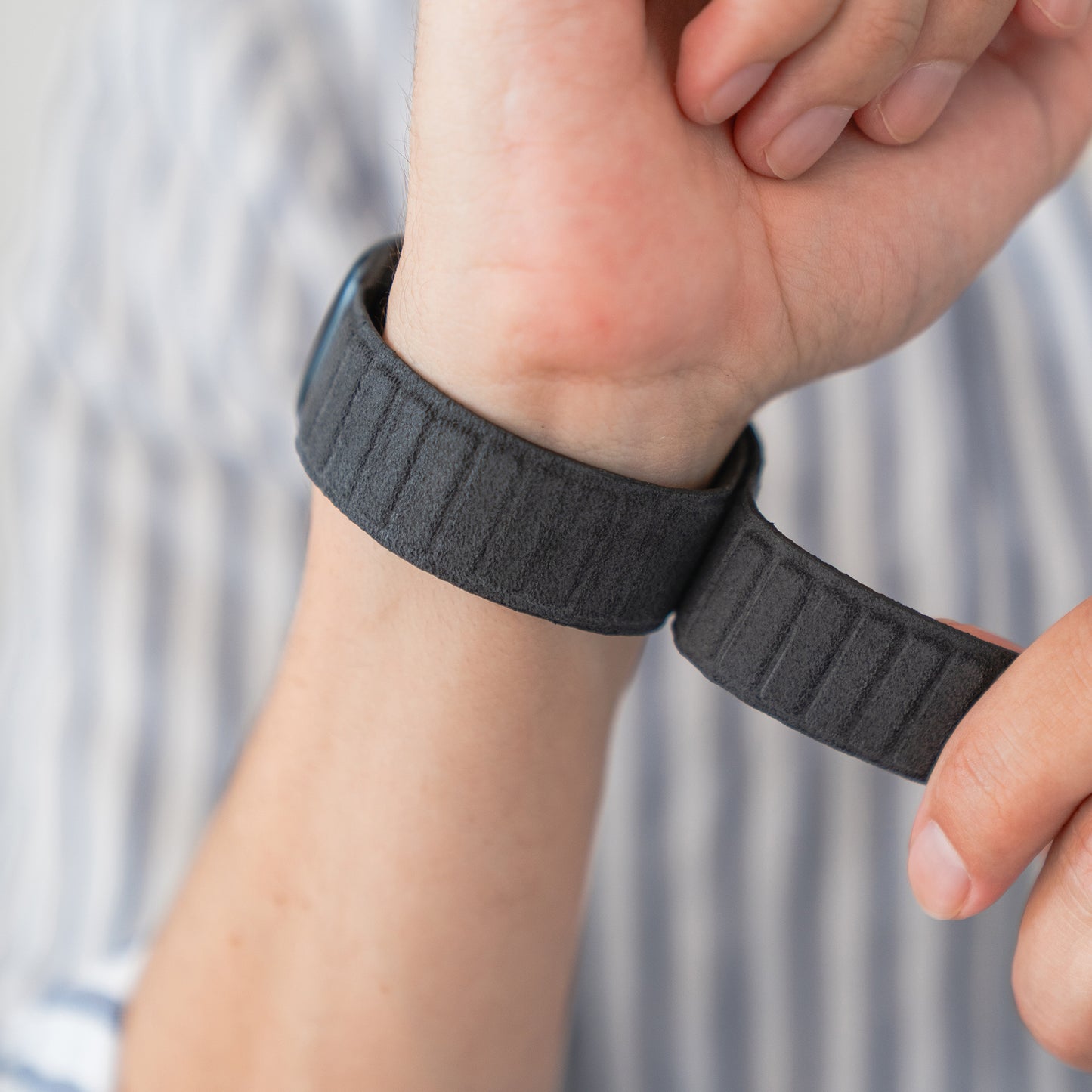 Eine Person legt sich das arktisband Apple Watch magnetisches Armband aus Alcantara von arktisband um das Handgelenk und genießt einen Hauch von italienischem Lebensgefühl.
