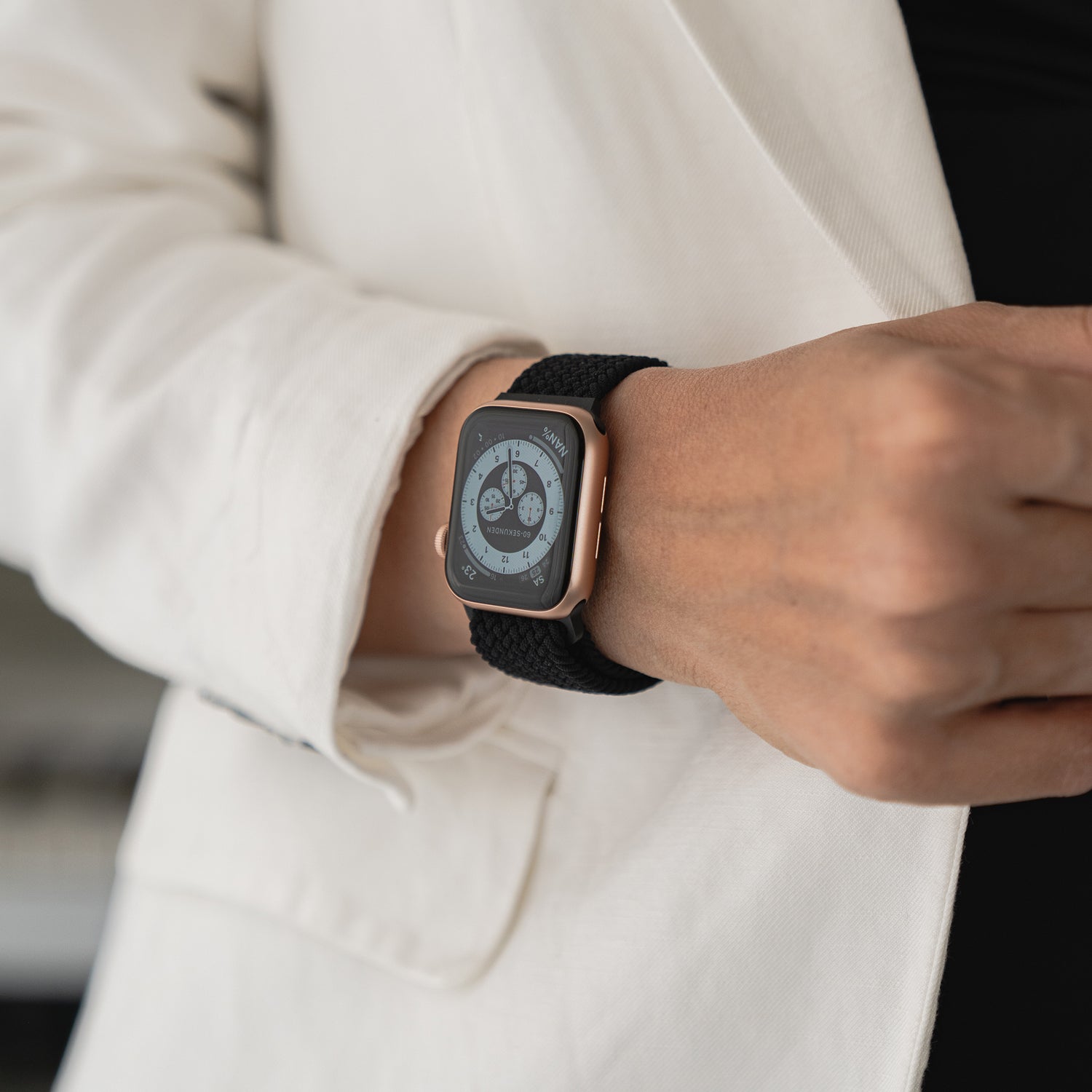 Person trägt ein kunstvoll geflochtenes Apple Watch Armband „Casual“ mit Magnetverschluss in Schwarz, kombiniert mit einem hellen Anzug.