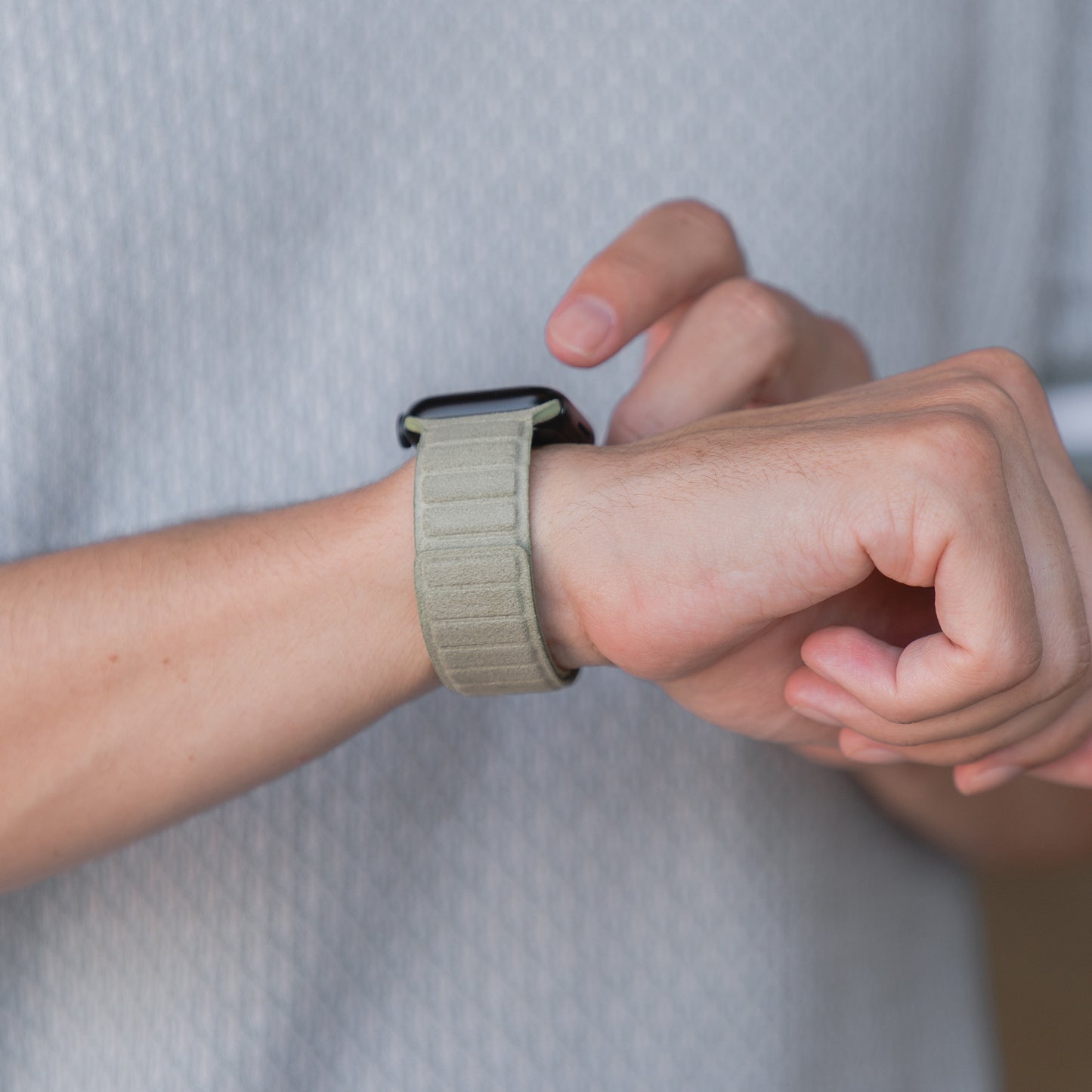 Eine Person, die das Arktisband Apple Watch magnetisches Armband aus Alcantara trägt, tippt auf ihre Uhr und fängt echtes italienisches Lebensgefühl in jeder Geste ein.