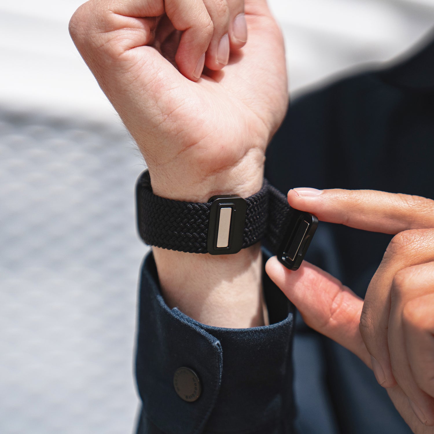 Jemand befestigt das arktisband Geflochtenes Apple Watch Armband "Casual" mit Magnetverschluss von arktisband, ein schwarzes geflochtenes Band mit Magnetverschluss, am linken Handgelenk.