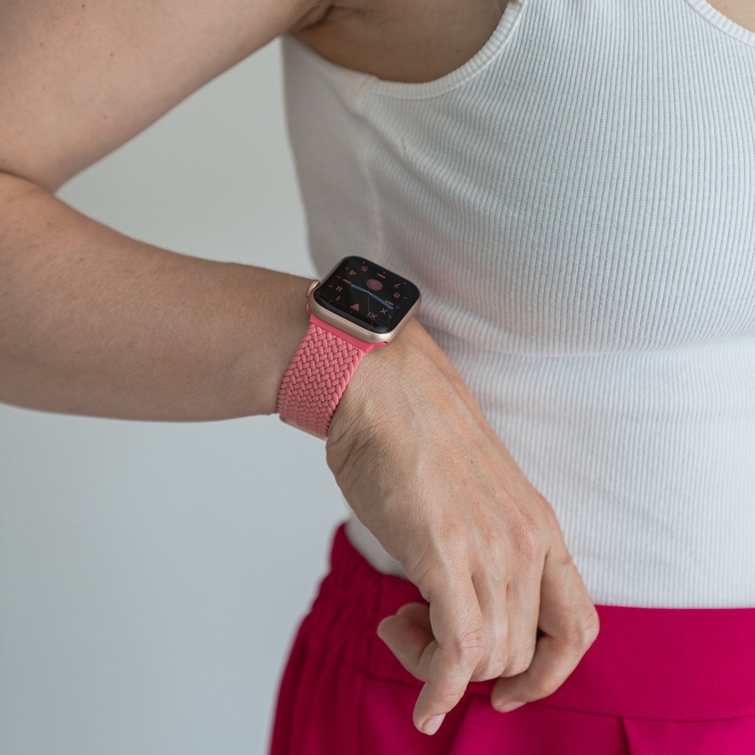Eine Person im weißen Tanktop und rosa Hosen trägt am Handgelenk das arktisband Geflochtenes Apple Watch Armband „Casual“ mit Magnetverschluss von arktisband.