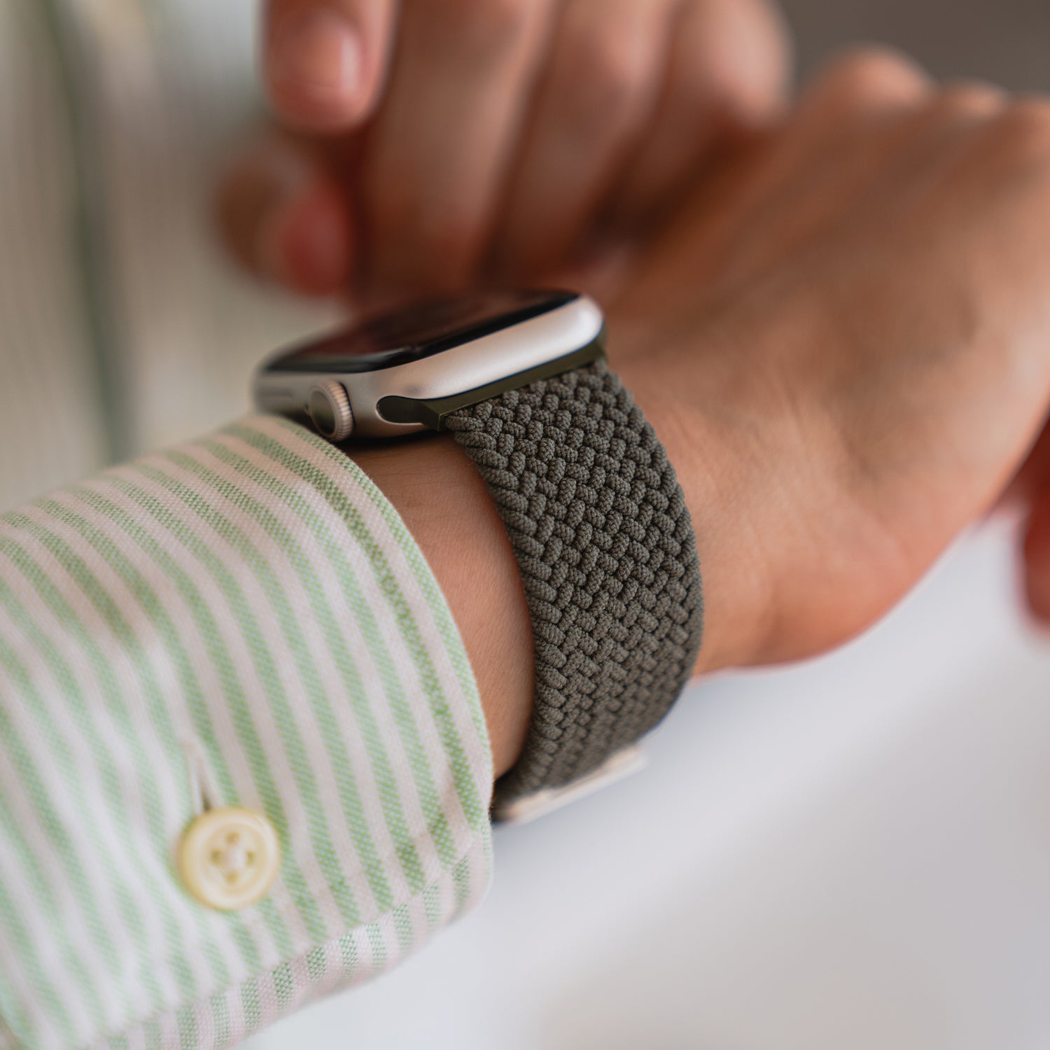 Jemand trägt das geflochtene Apple Watch Armband „Casual“ mit Magnetverschluss von arktisband und tippt mit der anderen Hand auf den Bildschirm der Uhr.