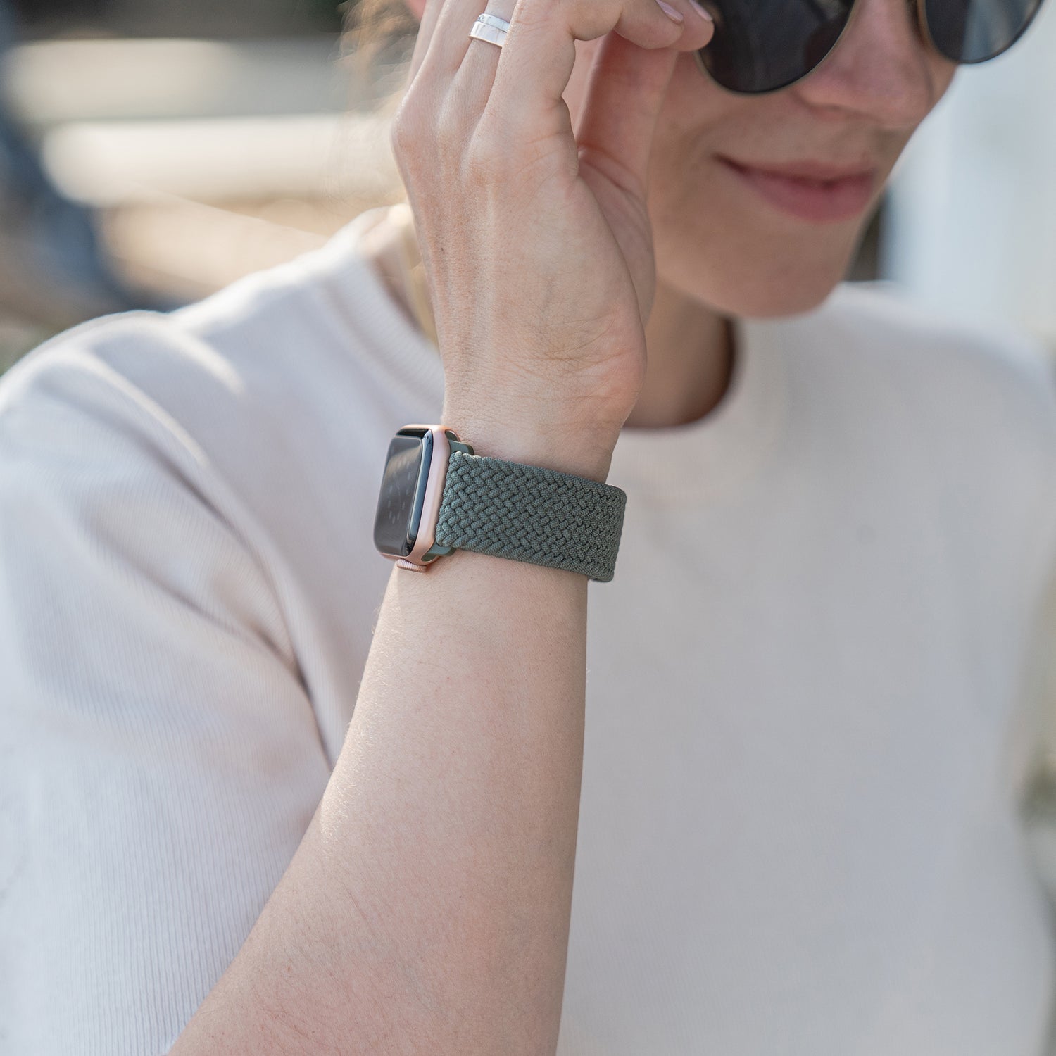 Frau trägt Sonnenbrille, ein helles Shirt und das arktisband Geflochtenes Apple Watch Armband „Casual“ in Grün mit Magnetverschluss von arktisband.