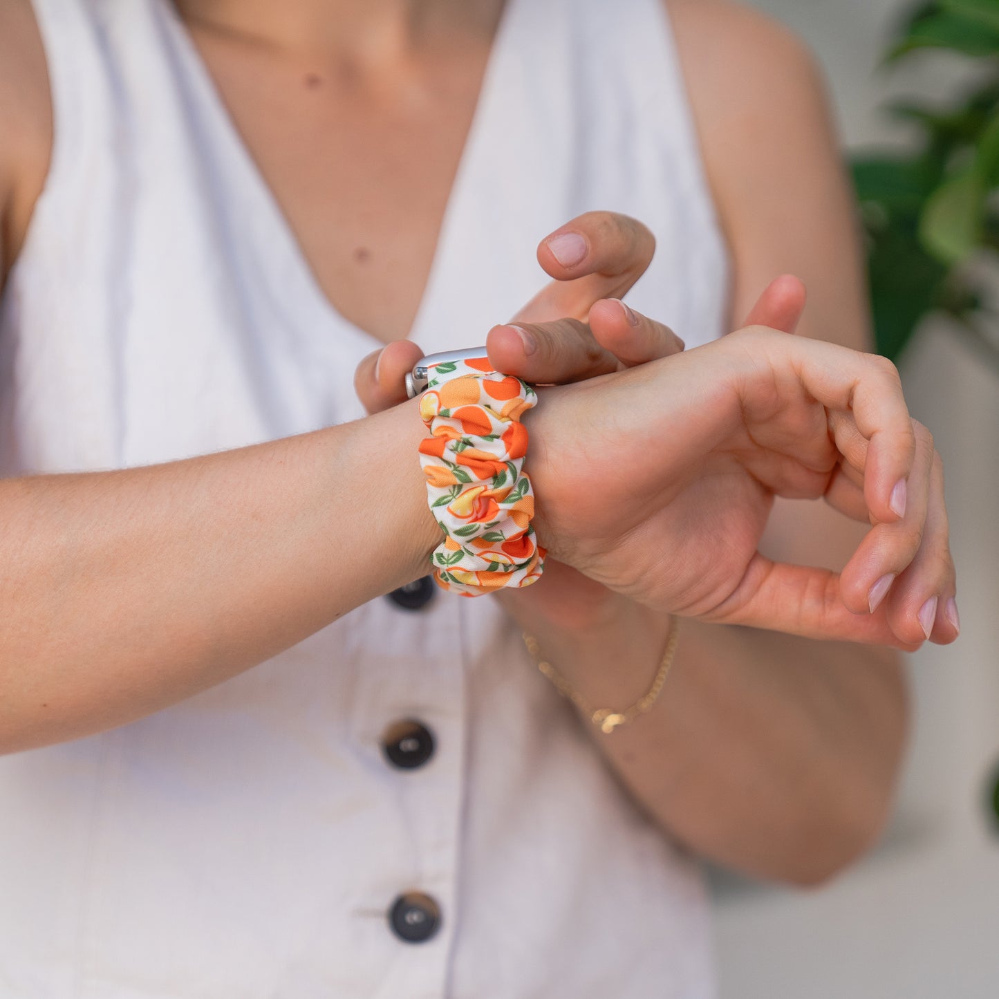 Eine Person, die ein weißes ärmelloses Oberteil trägt, passt das arktisband Apple Watch Scrunchie Armband "Elanora" an ihr Handgelenk an.