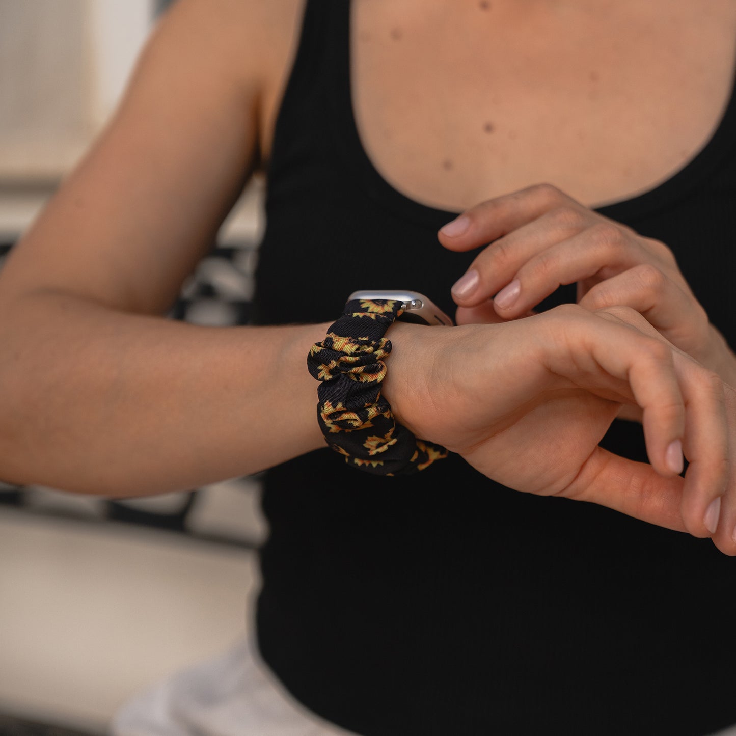 Person, die ein Arktisband Apple Watch Scrunchie Armband "Elanora" in Schwarz und Gelb trägt und den Bildschirm berührt.