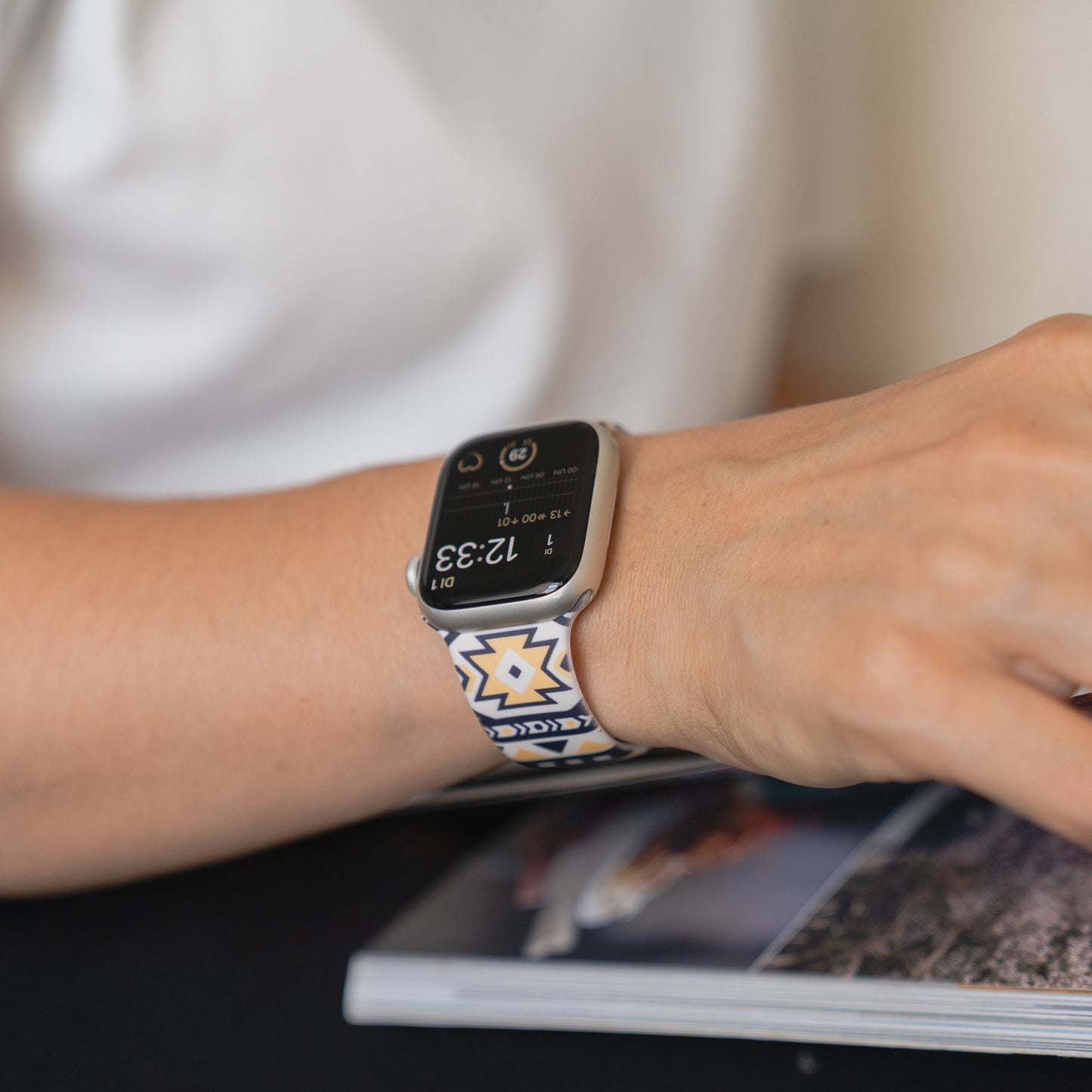 Arktisband EDITION für Apple Watch mit Silikonarmband von arktisband am Handgelenk einer Person, die ihre Hand auf ein geöffnetes Magazin legt.