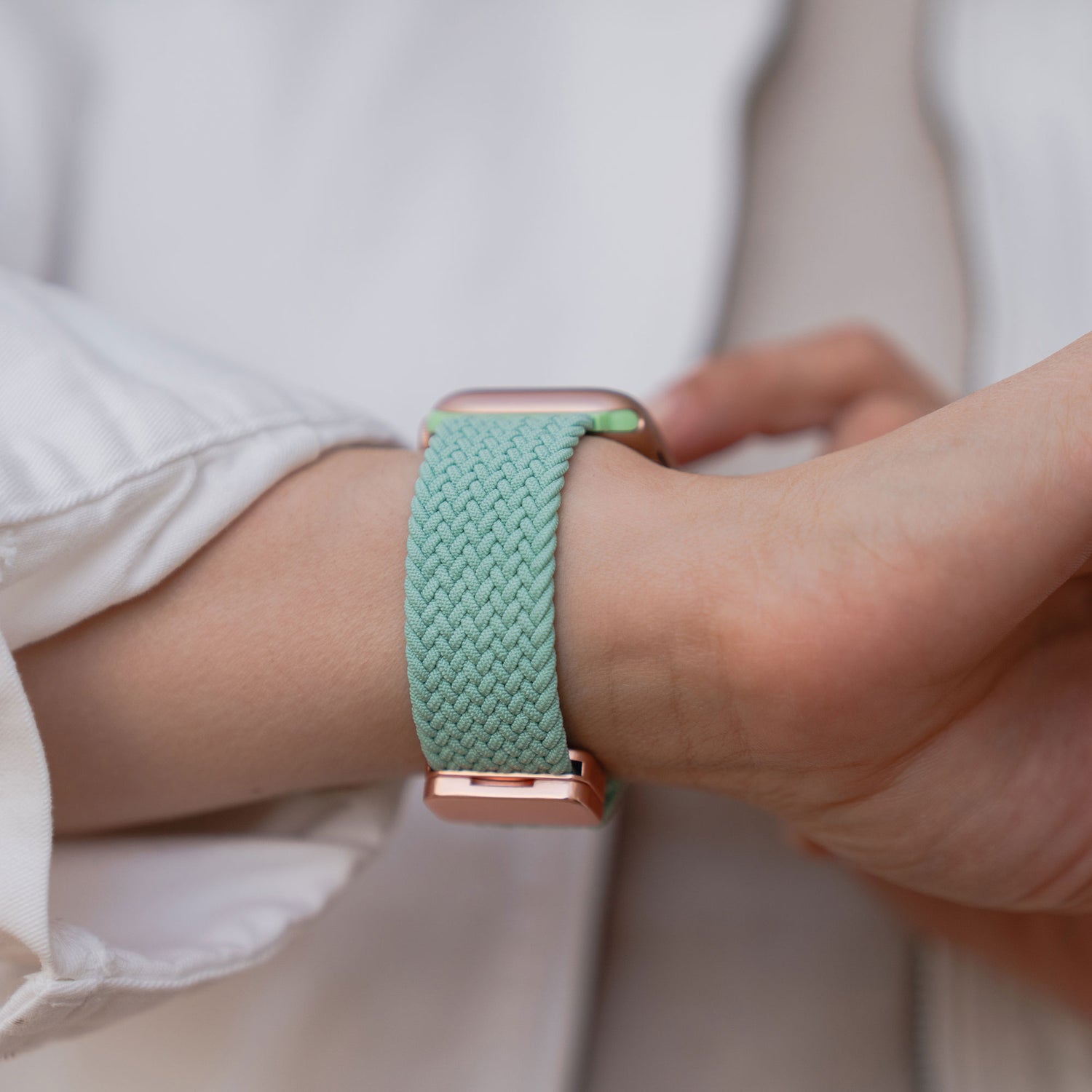 Eine Person trägt ein arktisbandgeflochtenes Apple Watch Armband „Casual“ mit Magnetverschluss in Hellgrün am Handgelenk.