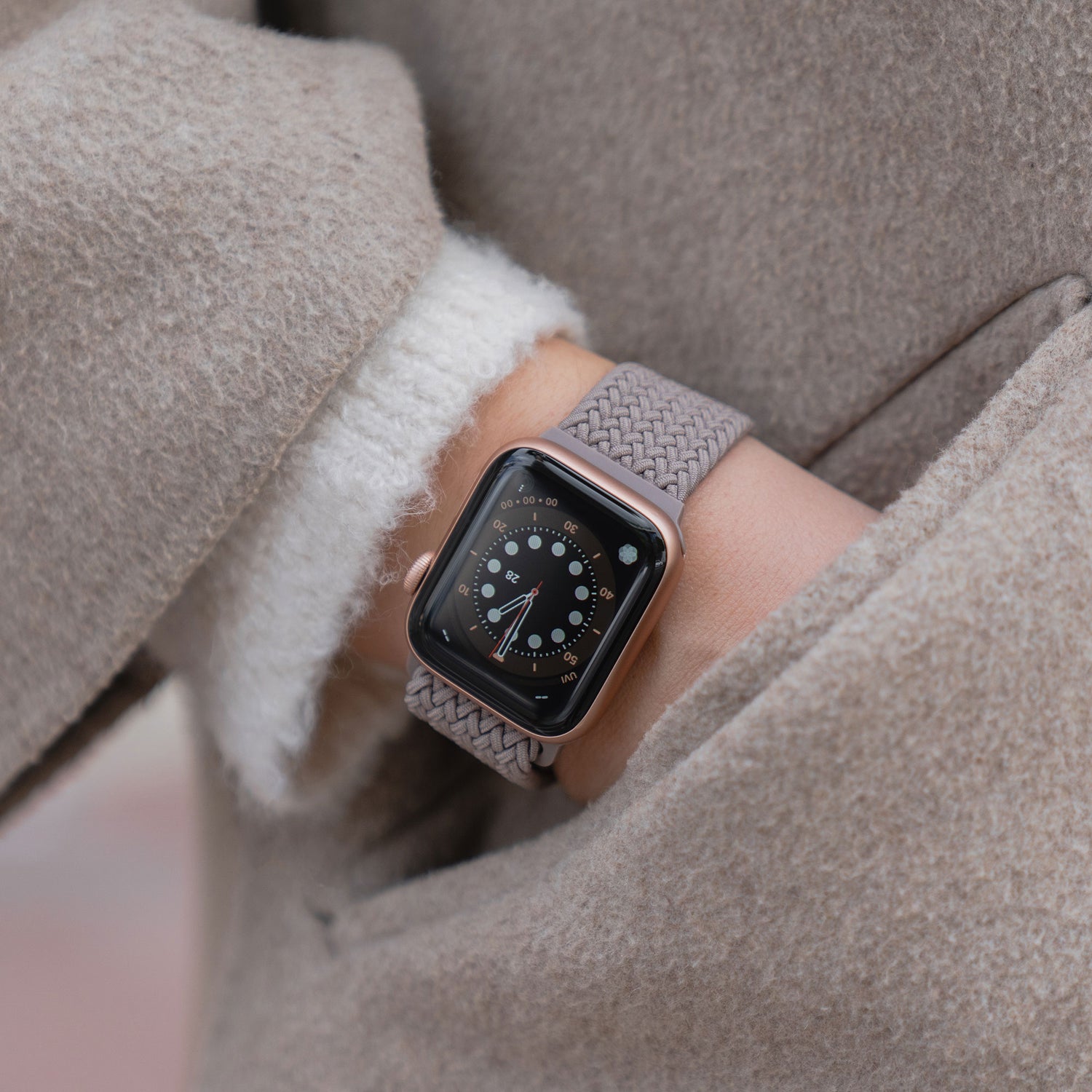 Nahaufnahme einer Person, die ein von Arktisband geflochtenes Apple Watch Armband „Casual“ mit Magnetverschluss trägt und ihre Hand in einer beigen Manteltasche hat.