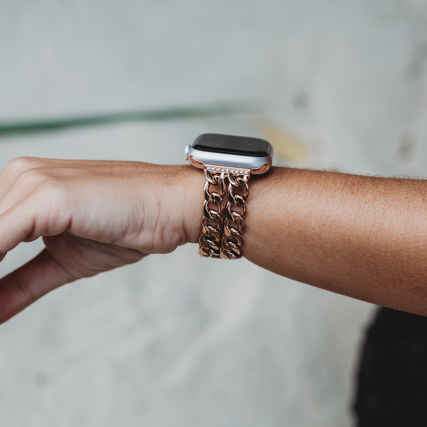 Jemand trägt das arktisband Apple Watch Armband „Princess“ von arktisband – mit einem dicken, goldfarbenen, glänzenden Kettenglieddesign – am Handgelenk vor einem sanft verschwommenen hellen Hintergrund.