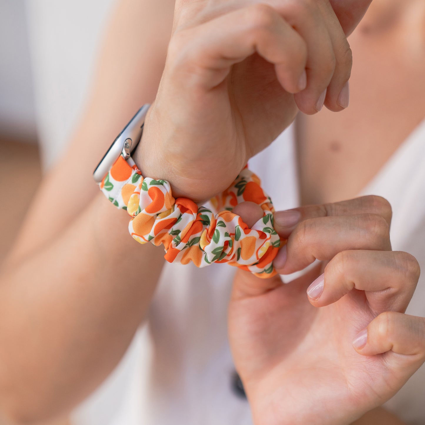 Eine Person trägt das arktisband Apple Watch Scrunchie Armband "Elanora" mit einem orangefarbenen Muster als Apple Watch Band.
