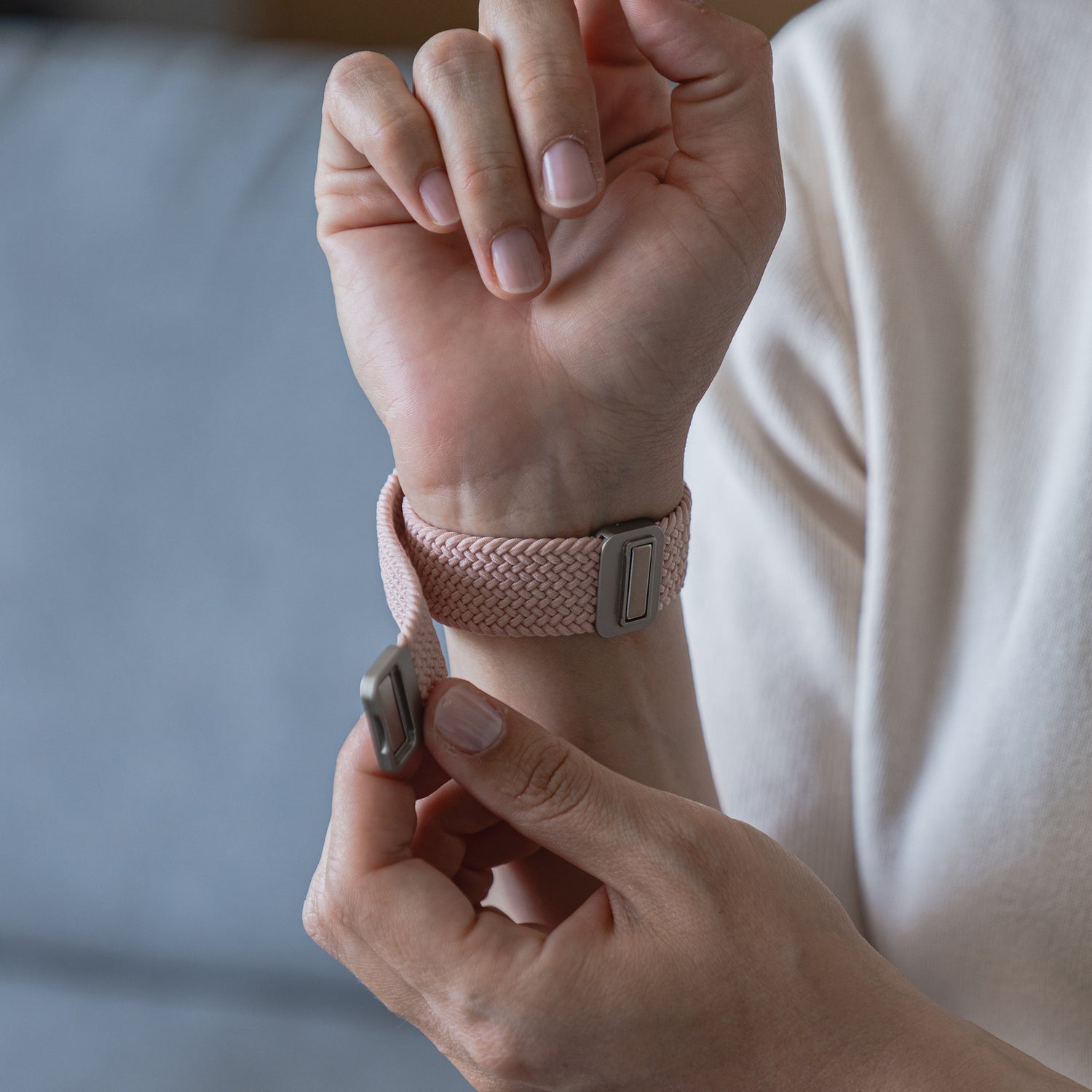 Eine Person befestigt das arktisband Geflochtene Apple Watch Armband „Casual“ mit Magnetverschluss in Pink am linken Handgelenk.