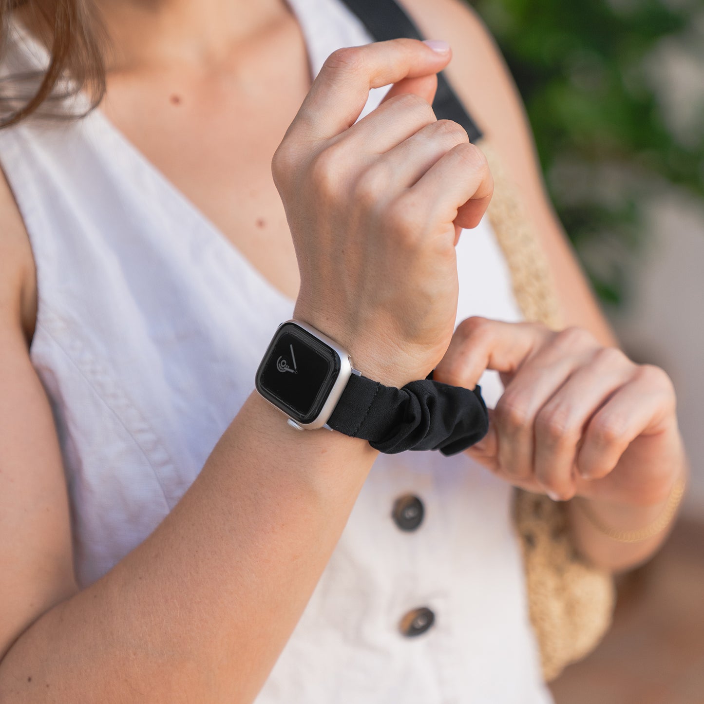 Eine Person, die das arktisband Apple Watch Scrunchie Armband "Elanora" von arktisband trägt, passt das stylische schwarze Gummiband an ihrem Handgelenk an.