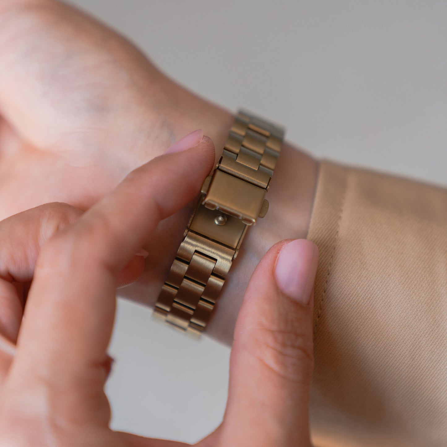 Eine Person befestigt mit der rechten Hand ein arktisband Apple Watch Gliederarmband „Arctica“ – Slim von arktisband am linken Handgelenk.