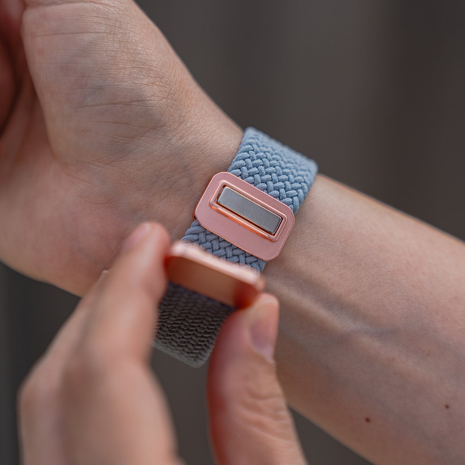Eine Person befestigt das arktisband Geflochtene Apple Watch Armband „Casual“ mit Magnetverschluss in Roségold an ihrem Handgelenk.