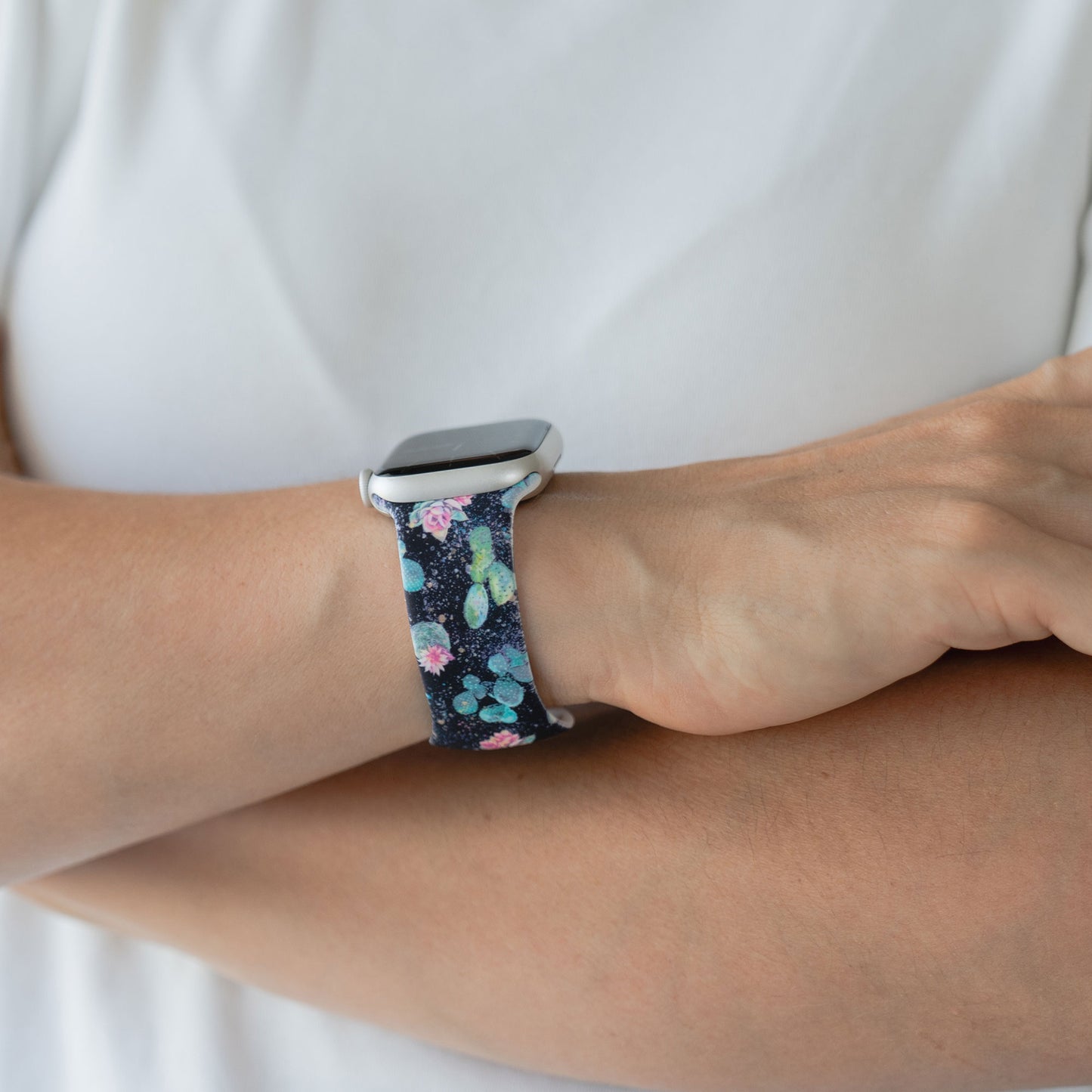 Eine Person trägt eine arktisband EDITION für Apple Watch, ein dunkles, floral gemustertes Armband von arktisband, an ihrem Handgelenk.