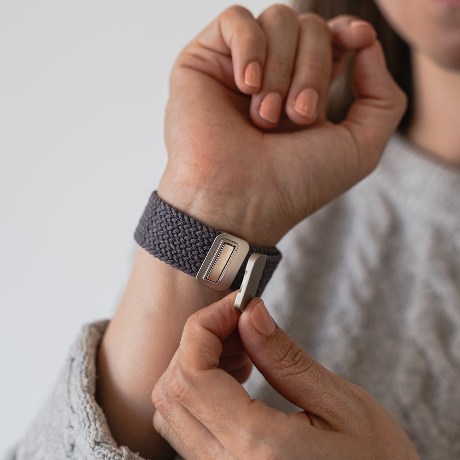 Jemand befestigt das arktisband Geflochtene Apple Watch Armband „Casual“ mit Magnetverschluss, ein gewebtes dunkelgraues Band von arktisband, um sein Handgelenk.