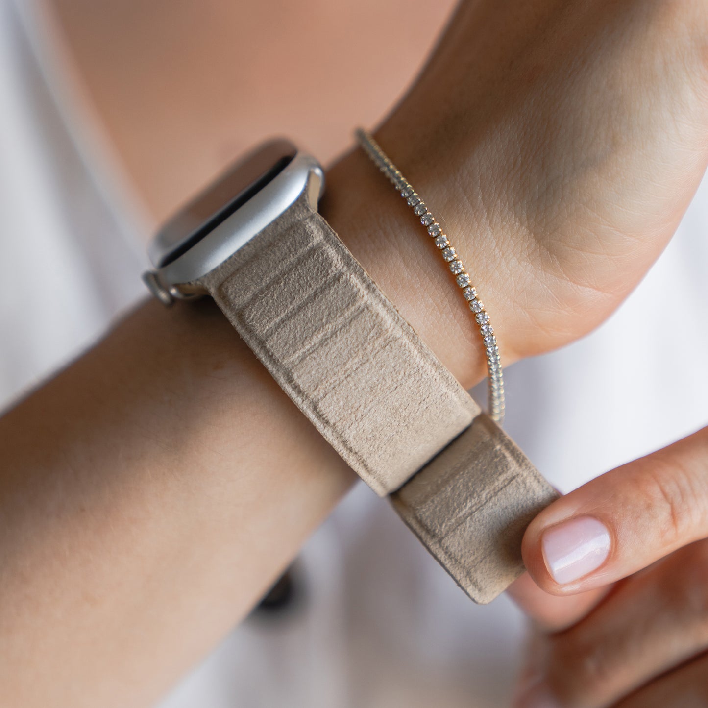 Nahaufnahme einer Person, die eine arktisband Apple Watch magnetisches Armband aus Alcantara von arktisband trägt, gepaart mit einem zarten Diamantarmband.