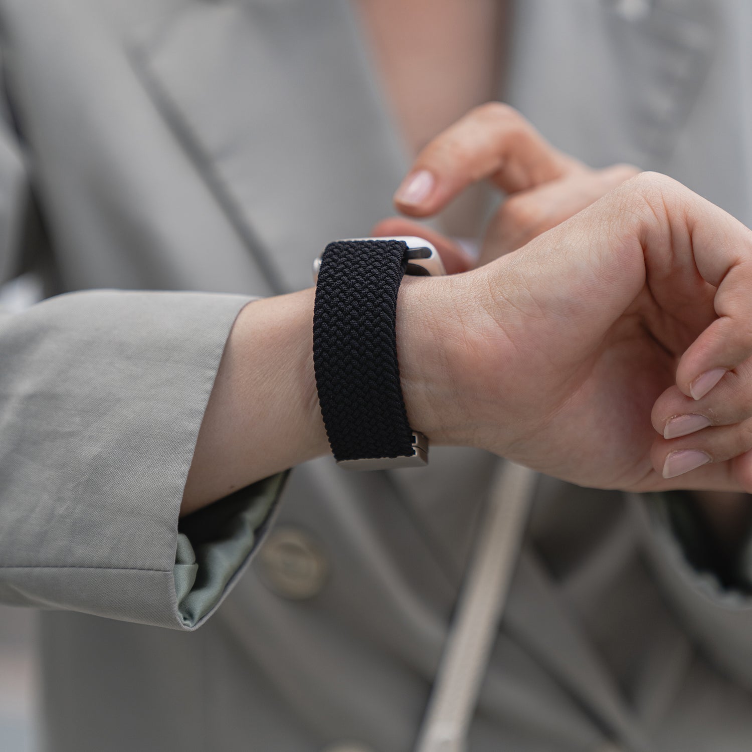 Eine Person in einem grauen Blazer passt ein von Arktisband geflochtenes Apple Watch Armband „Casual“ mit Magnetverschluss an ihr Handgelenk.