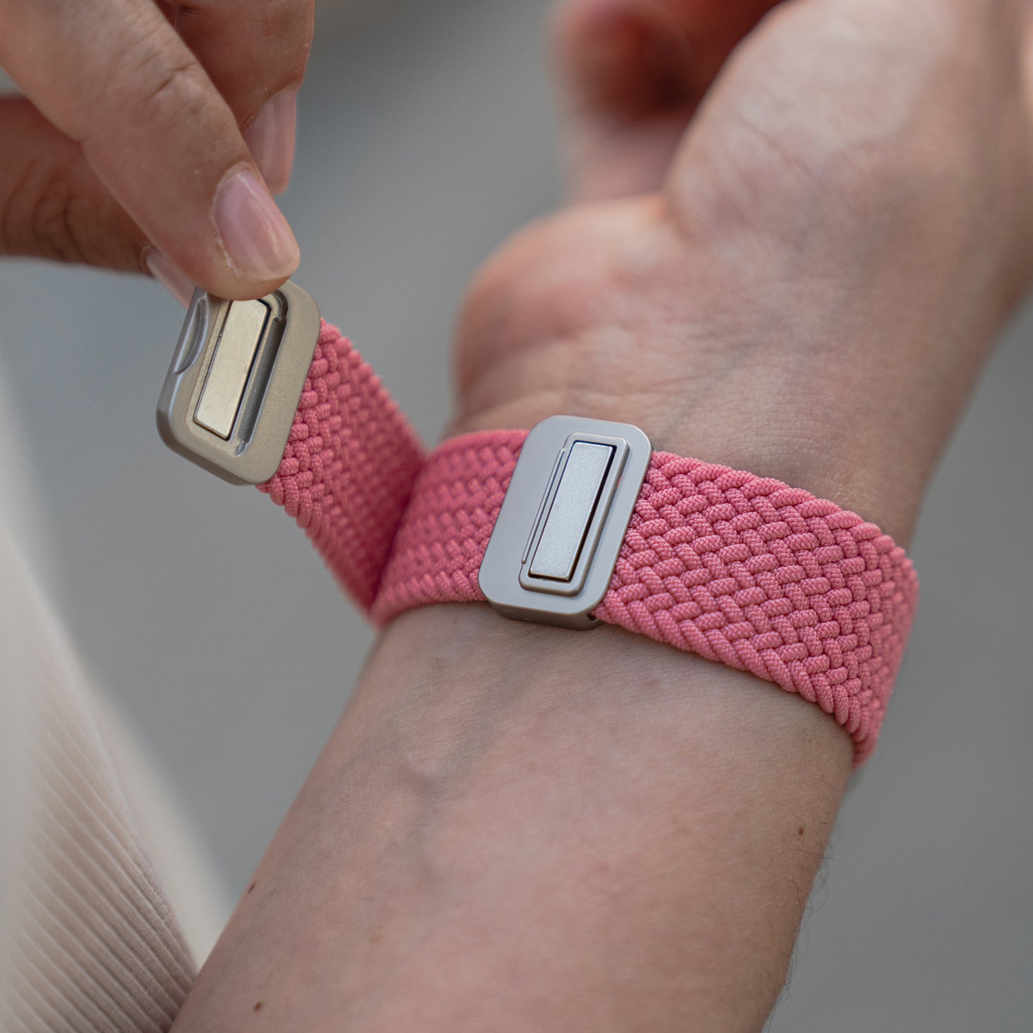 Eine Person befestigt ein von artisband geflochtenes Apple Watch Armband „Casual“ mit einem metallischen Magnetverschluss an ihrem Handgelenk.