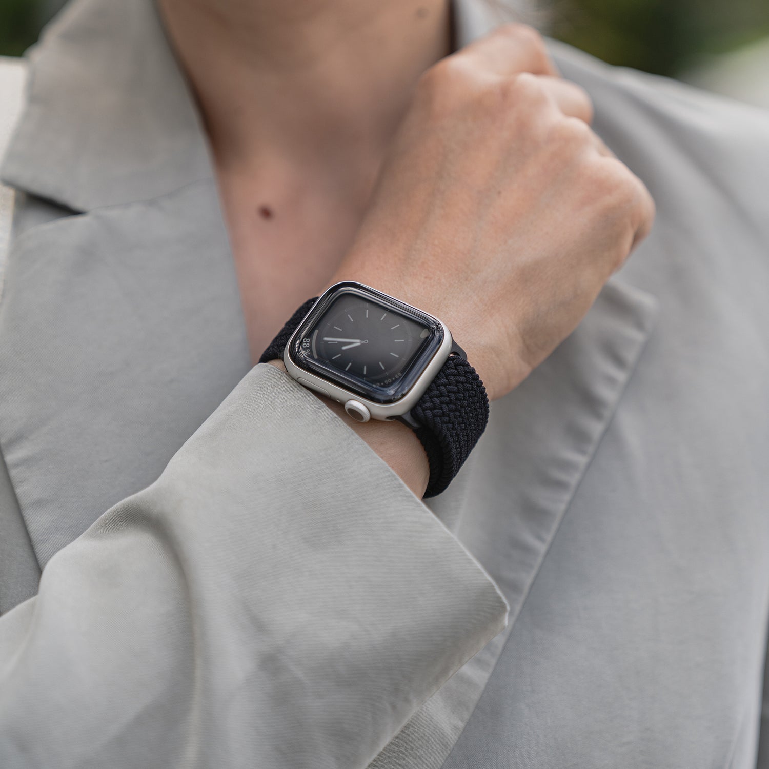 Nahaufnahme einer Person, die das geflochtene Apple Watch Armband „Casual“ mit Magnetverschluss von arktisband trägt, kombiniert mit einem hellgrauen Blazer.