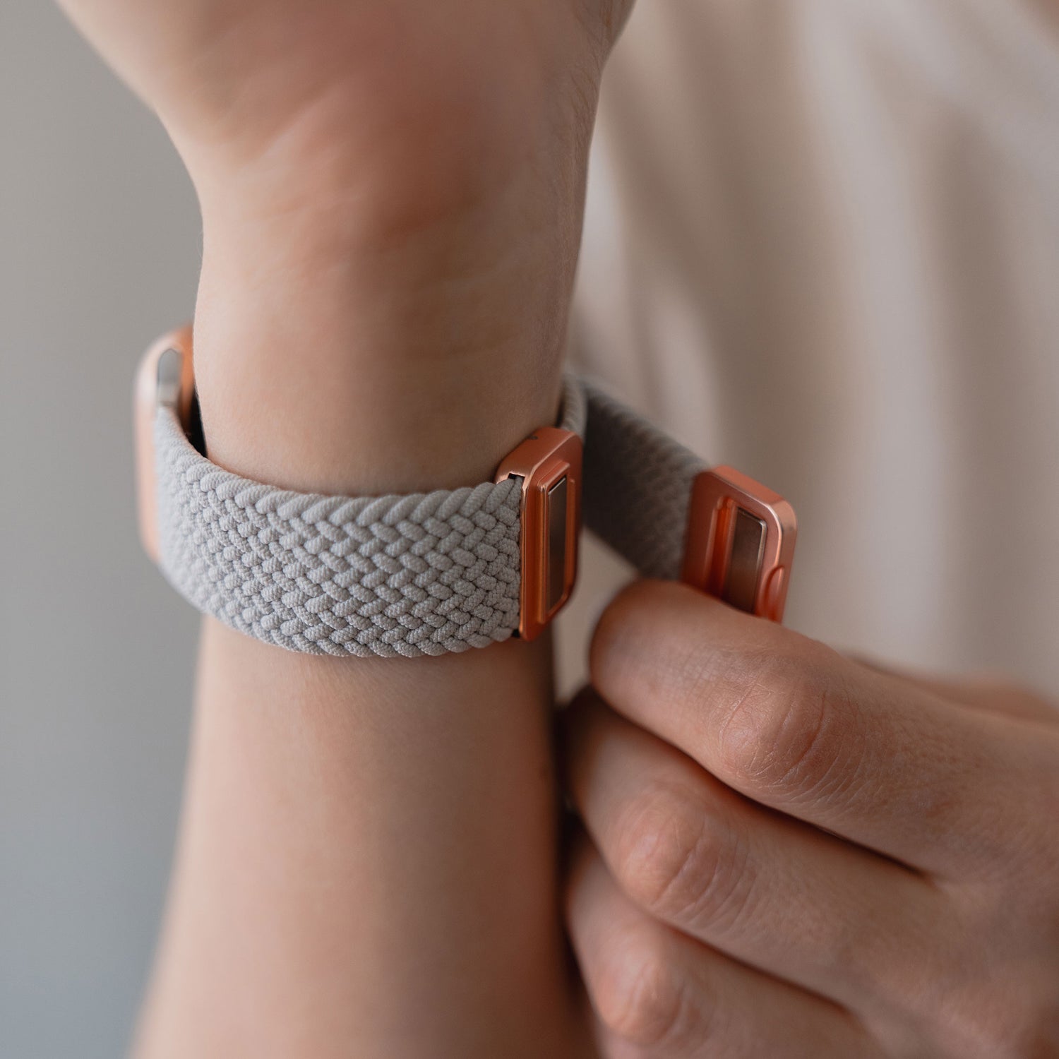 Eine Person befestigt das arktisband Geflochtenes Apple Watch Armband „Casual“ mit Magnetverschluss, ein gewebtes graues Band von arktisband, um ihr Handgelenk.