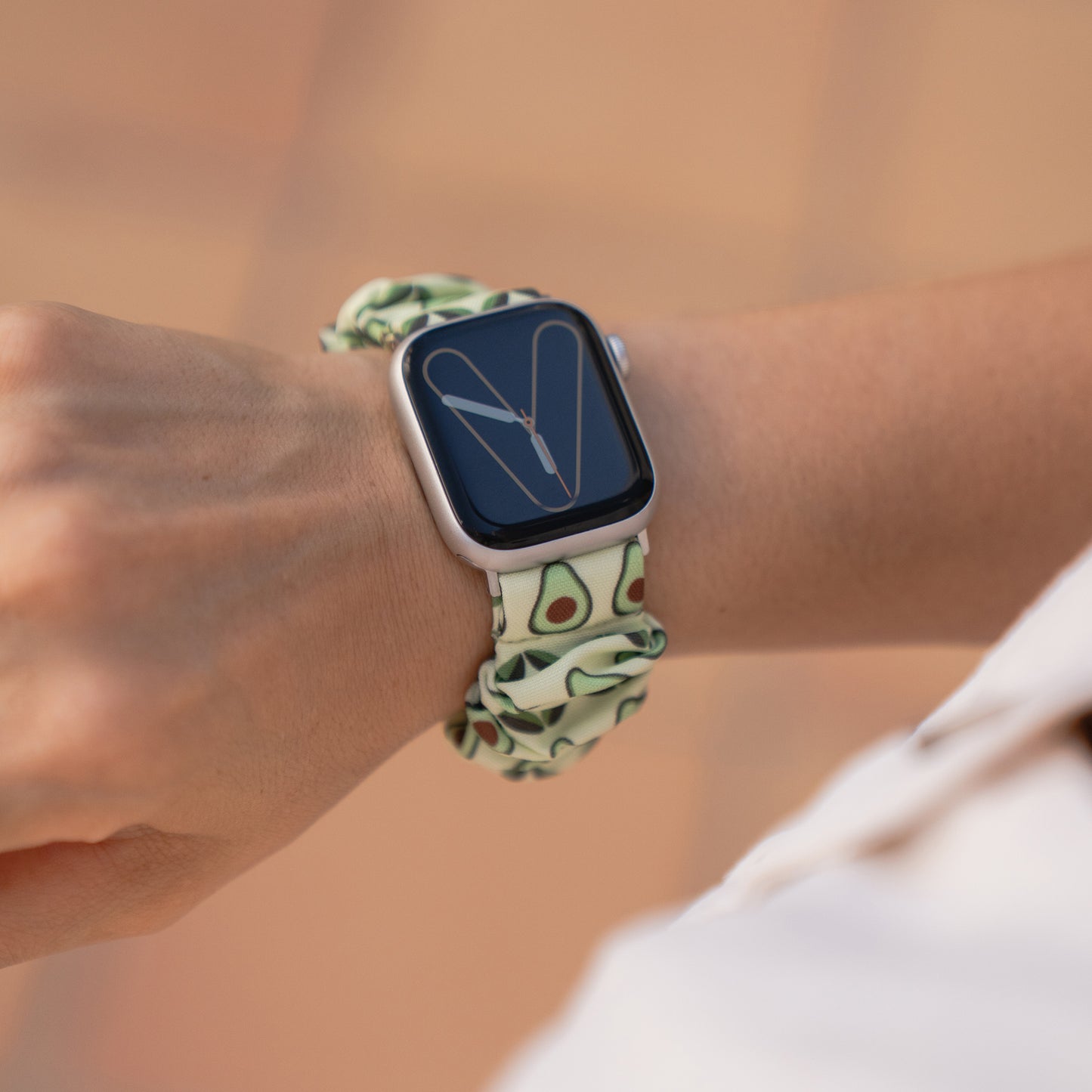 Eine Apple Watch mit dem arktisband "Elanora" Avocado-Print Scrunchie Armband von arktisband am Handgelenk einer Person.