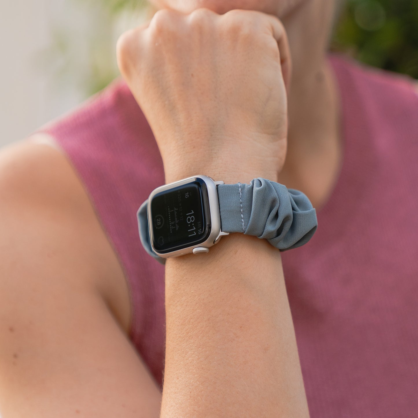 Eine Person trägt das arktisband Apple Watch Scrunchie Armband "Elanora" in Blau an ihrem Handgelenk, gestylt mit einem ärmellosen Oberteil.