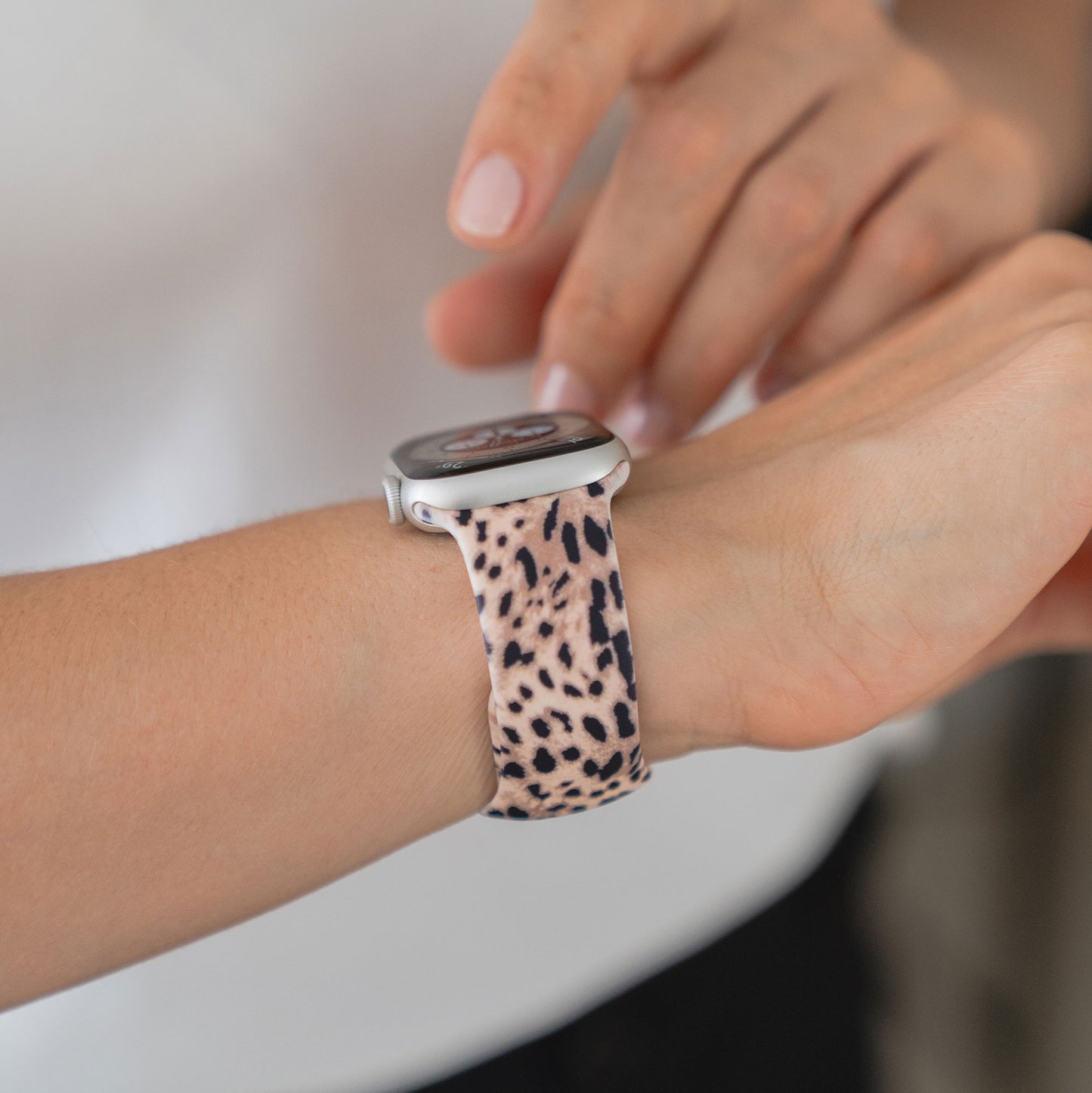 Eine Person, die ein arktisband EDITION for Apple Watch, ein Leopardenband von arktisband, trägt, tippt mit der anderen Hand auf den Bildschirm ihrer Smartwatch.