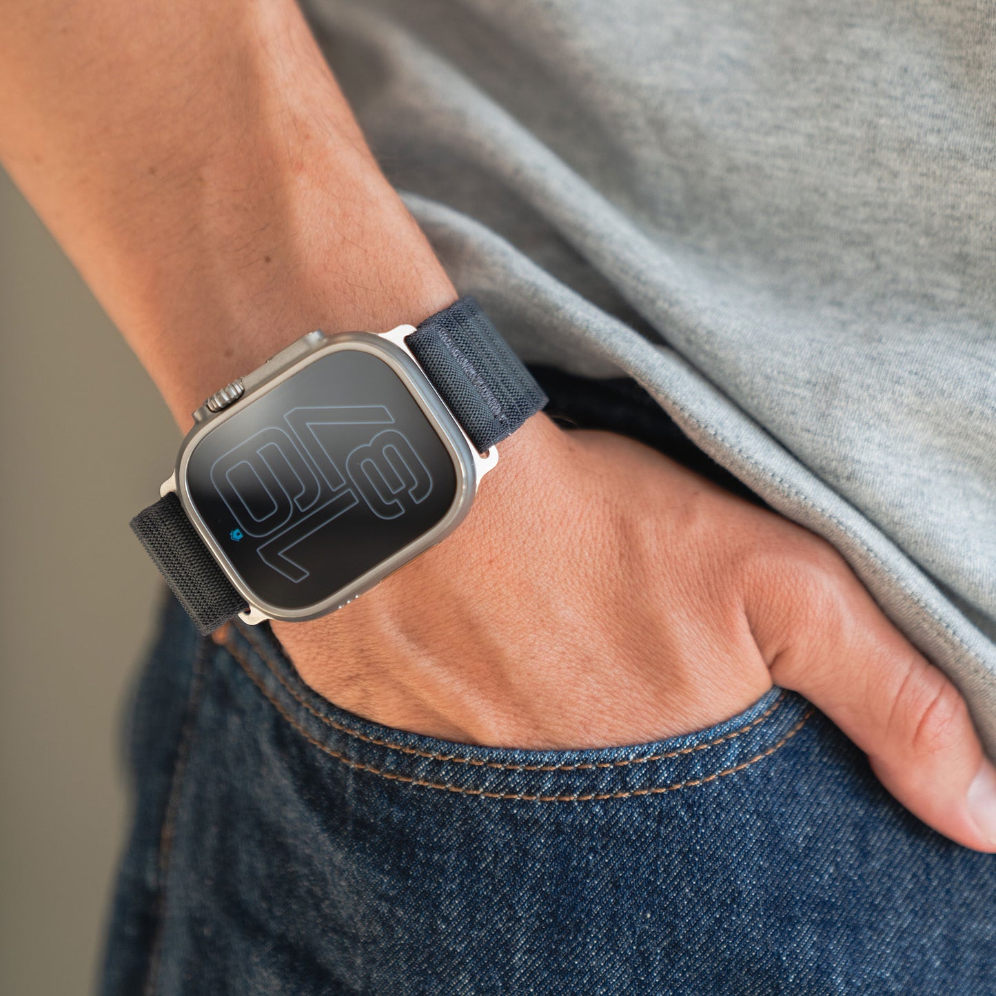 Person trägt das Künstlerarmband Apple Watch Nylon Armband „Venture“ mit schwarzem Wave-Look, Hand lässig in der Jeans-Tasche, kombiniert mit klassischem grauen Shirt – bereit fürs nächste Abenteuer.