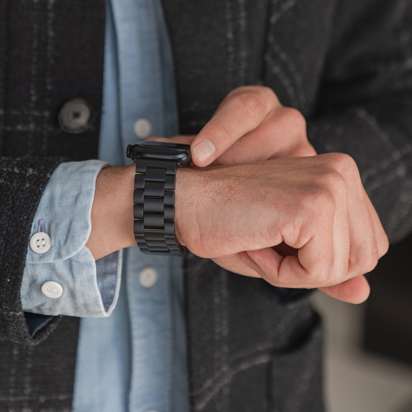 Person, die eine schwarze Smartwatch mit Metallarmband trägt und mit einem Finger auf den Bildschirm tippt.