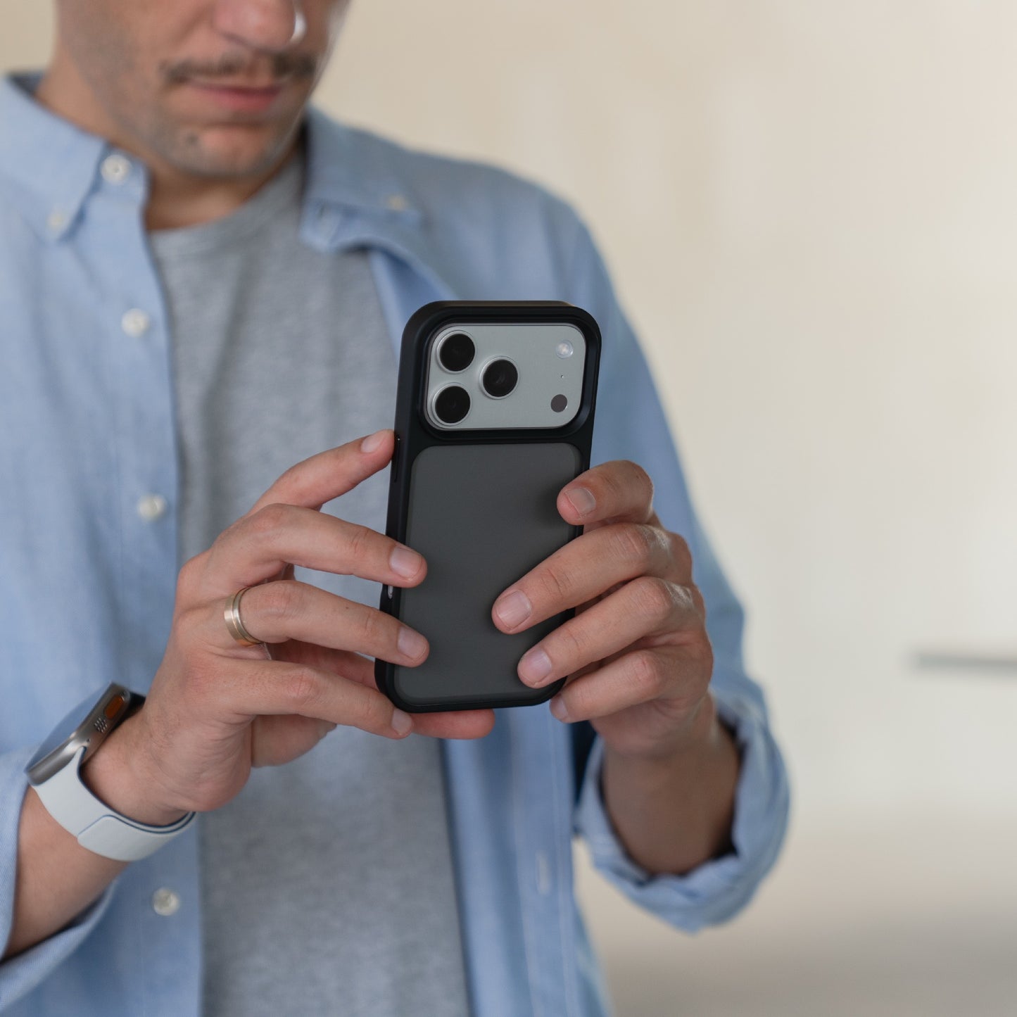 Eine Person hält ein Arktis iPhone 17 Pro Solid Case von Arktis waagerecht und bereitet sich auf eine Foto- oder Videoaufnahme in einem Innenraum vor.