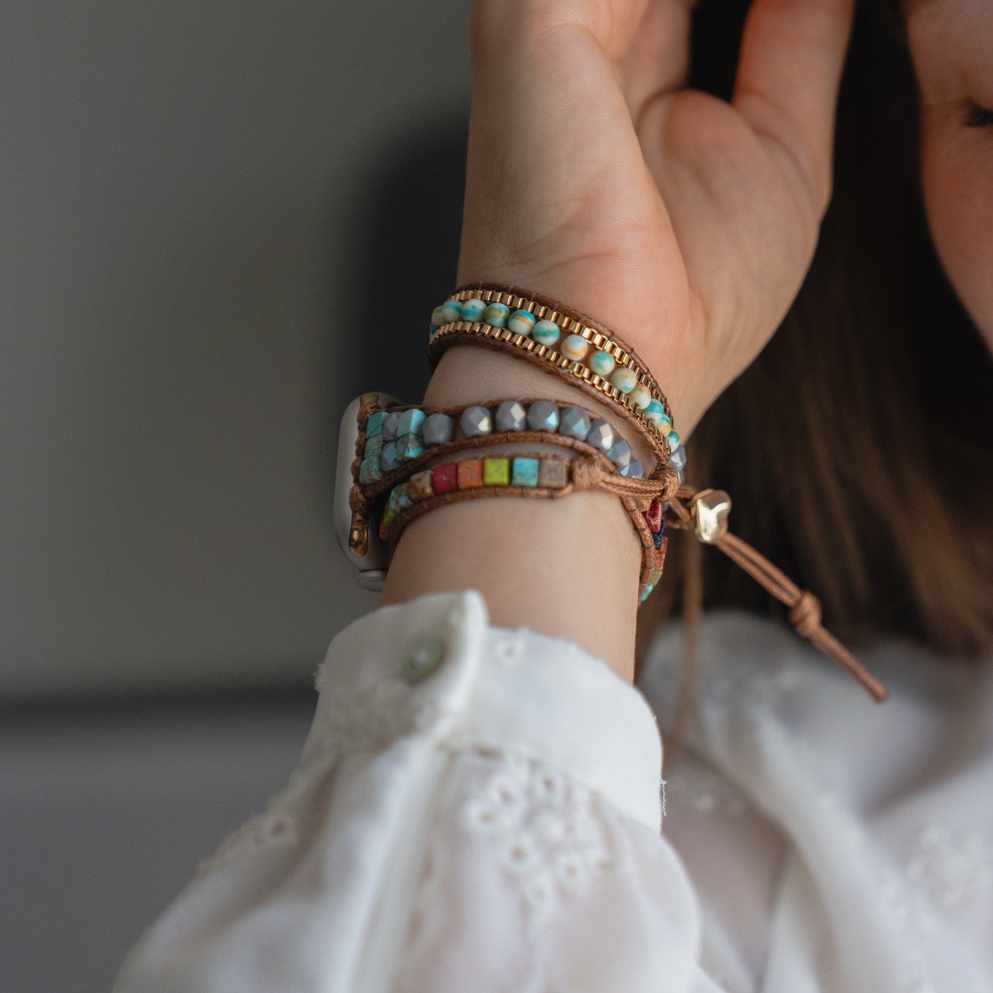 Eine Person trägt eine weiße Bluse und ein arktisband Apple Watch Armband "Dream Catcher" von arktisband mit bunten Perlen am Handgelenk.