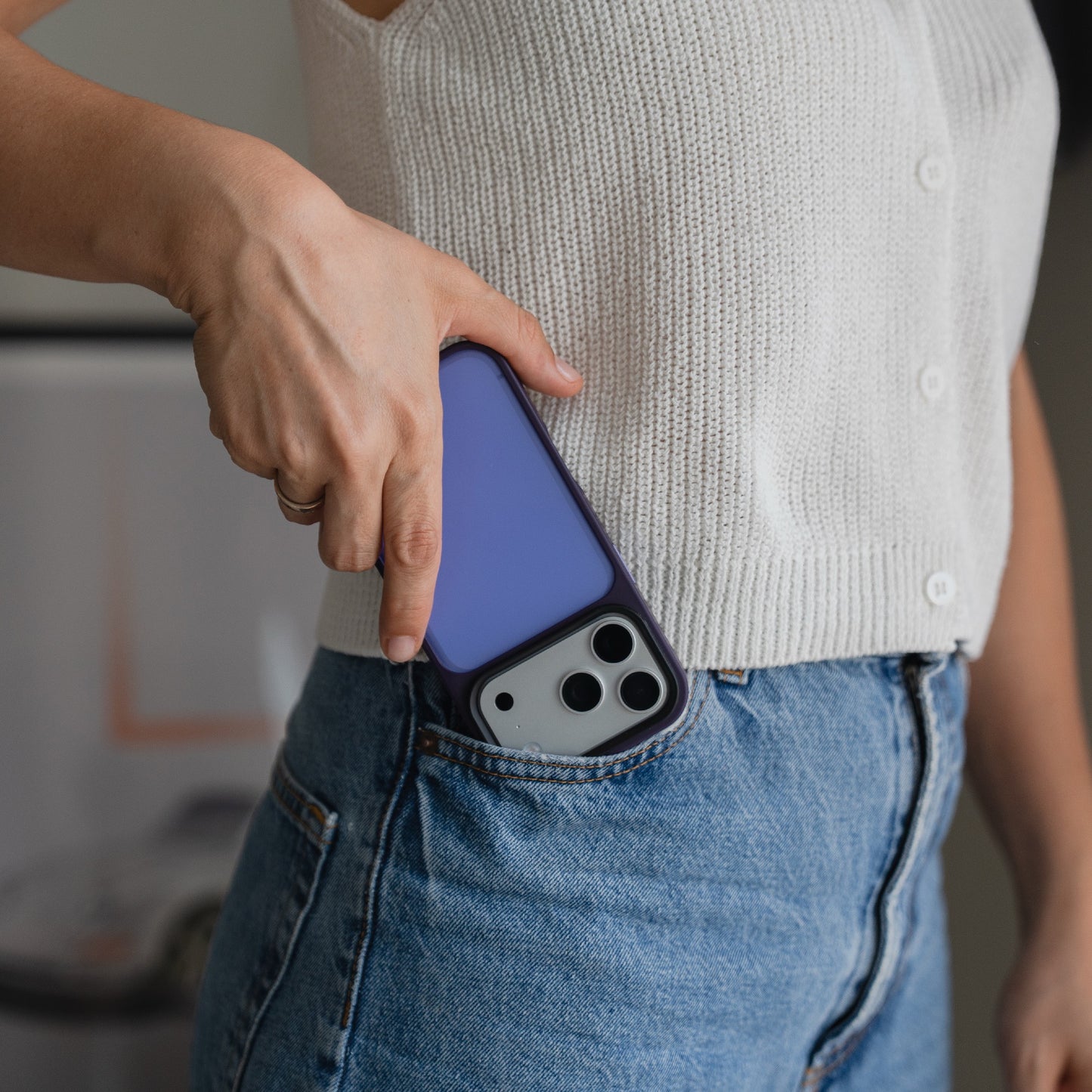 Eine Person in einem weißen Oberteil steckt ein Smartphone mit einem Arktis iPhone 17 Pro Solid Case in die Vordertasche einer blauen Jeans.
