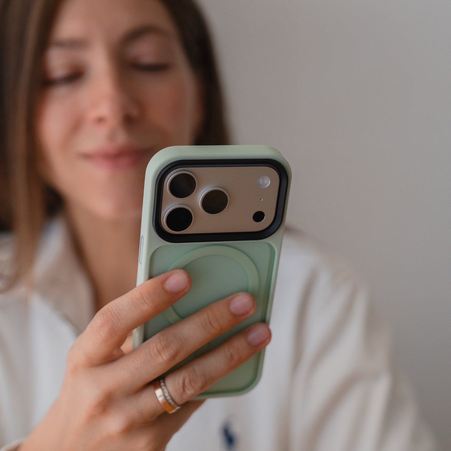 Eine Frau hält ein Arktis iPhone 17 Pro Solid Case mit MagSafe in Mintgrün und lächelt sanft in den Hintergrund.