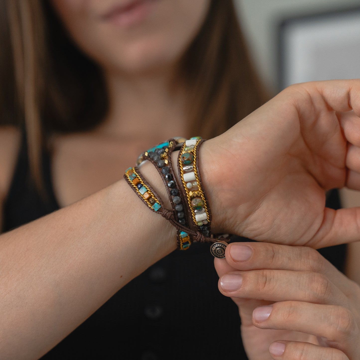 Eine Frau passt das arktisband Apple Watch Armband "Dream Catcher" mit farbenfrohem, elegantem Design an ihrem Handgelenk an und trägt ein schwarzes ärmelloses Oberteil.