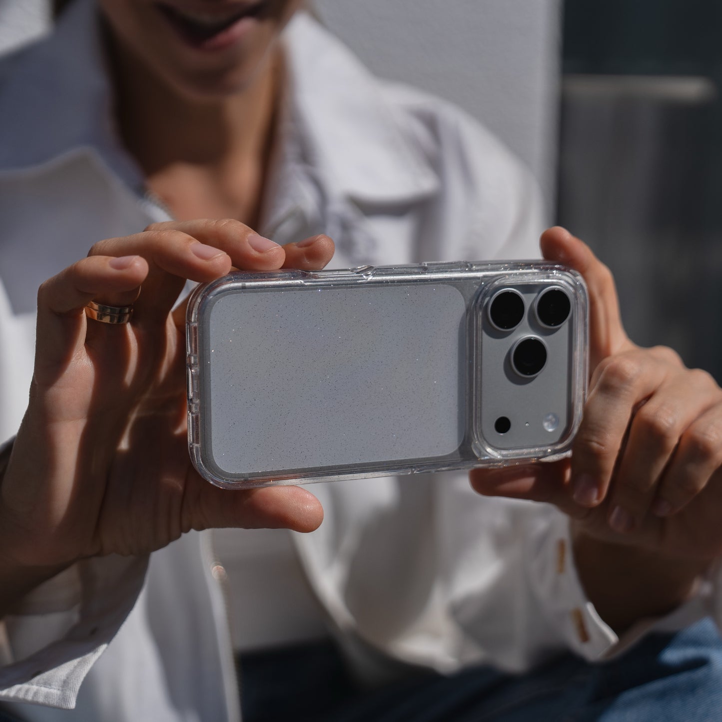 Eine Person hält ein arktis iPhone 17 Pro Max Glitter Case und ist bereit, ein Foto mit ihrem Smartphone zu machen, während sie ein weißes Hemd trägt.