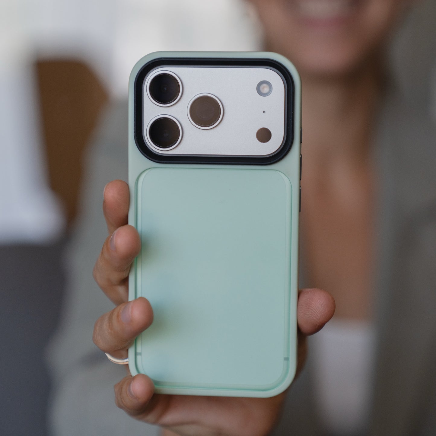 Eine Person hält das Arktis iPhone 17 Pro Solid Case von Arktis aus mintgrünem, mattem TPU-Silikon in der Hand, wobei die Kameralinsen nach vorne zeigen.