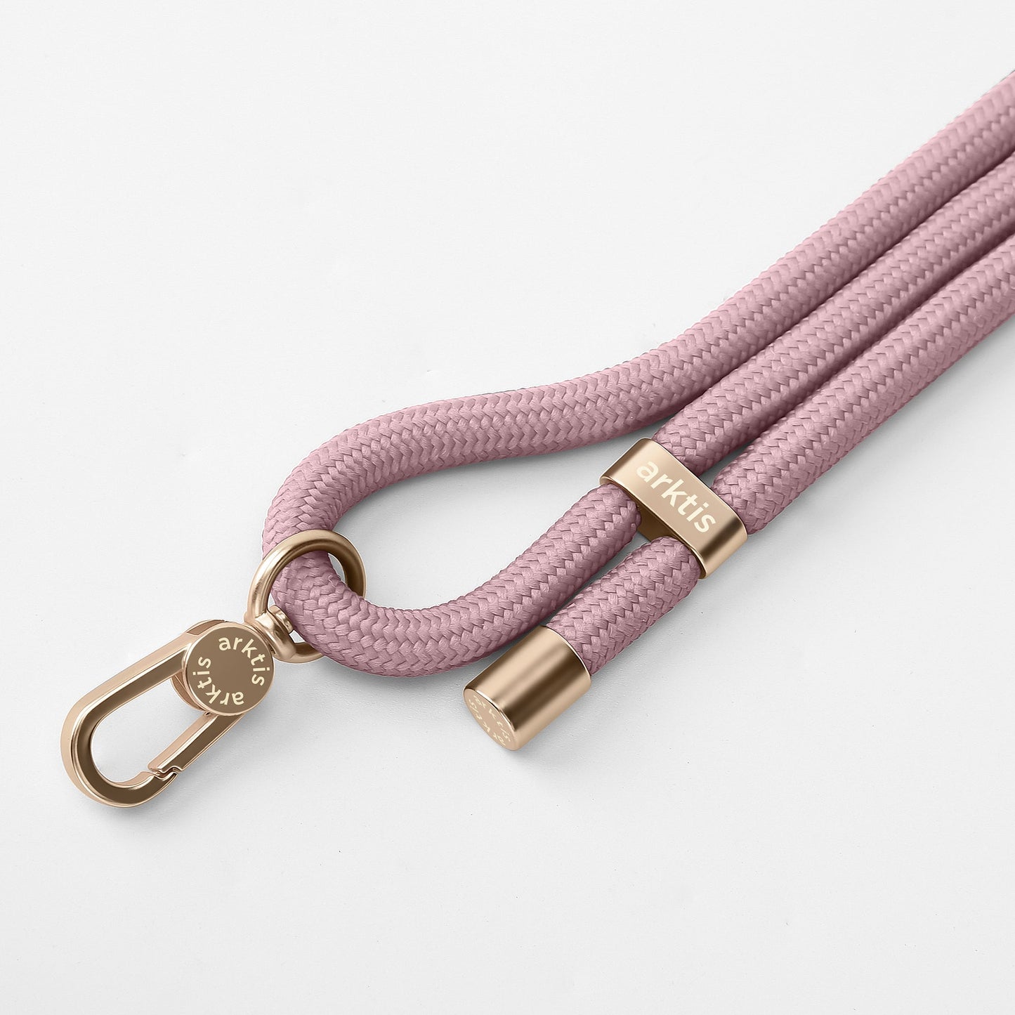 Die arktis Lanyard Handykette fürs Handgelenk von Arktis ist ein rosa geflochtenes Seilarmband mit goldenem Metallverschluss, Endkappen und einem runden Etikett mit der Gravur „arktis“ – ein stilvolles Smartphone-Zubehör auf weißem Hintergrund.