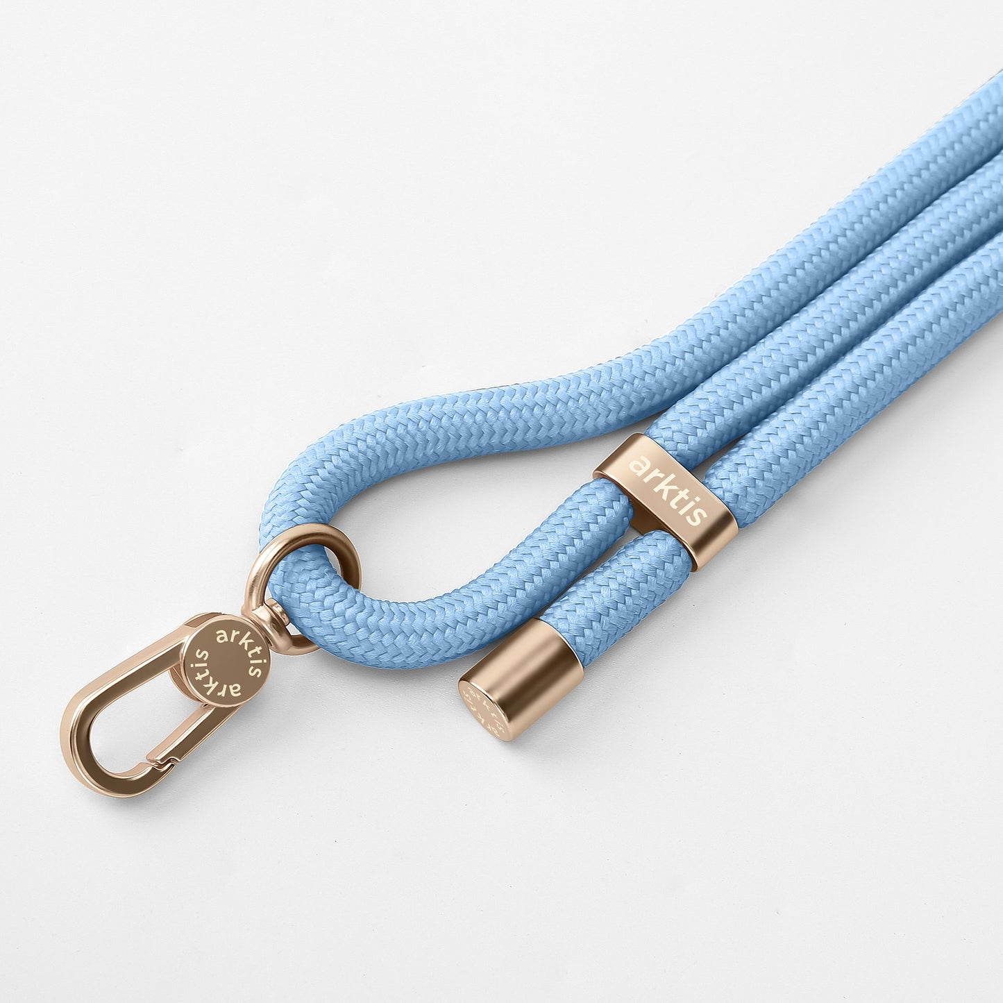 Die arktis Lanyard Handykette fürs Handgelenk von Arktis verfügt über eine schicke hellblaue geflochtene Kordel, goldene Metallakzente und einen Verschluss – was sie zum perfekten Smartphone-Accessoire und stylischen Modestück auf weißem Hintergrund macht.