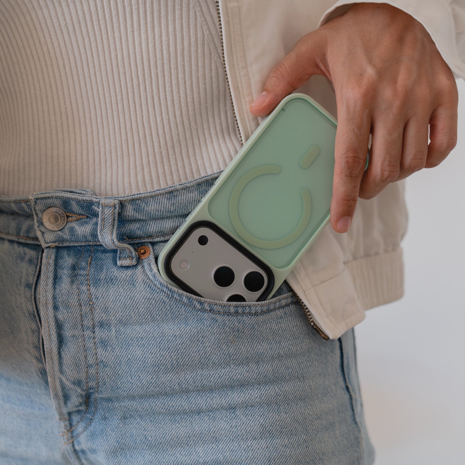 Eine Person steckt ein Arktis iPhone 17 Pro Solid Case mit MagSafe in Mintgrün, mit matter Oberfläche, in die Tasche einer hellblauen Jeans.