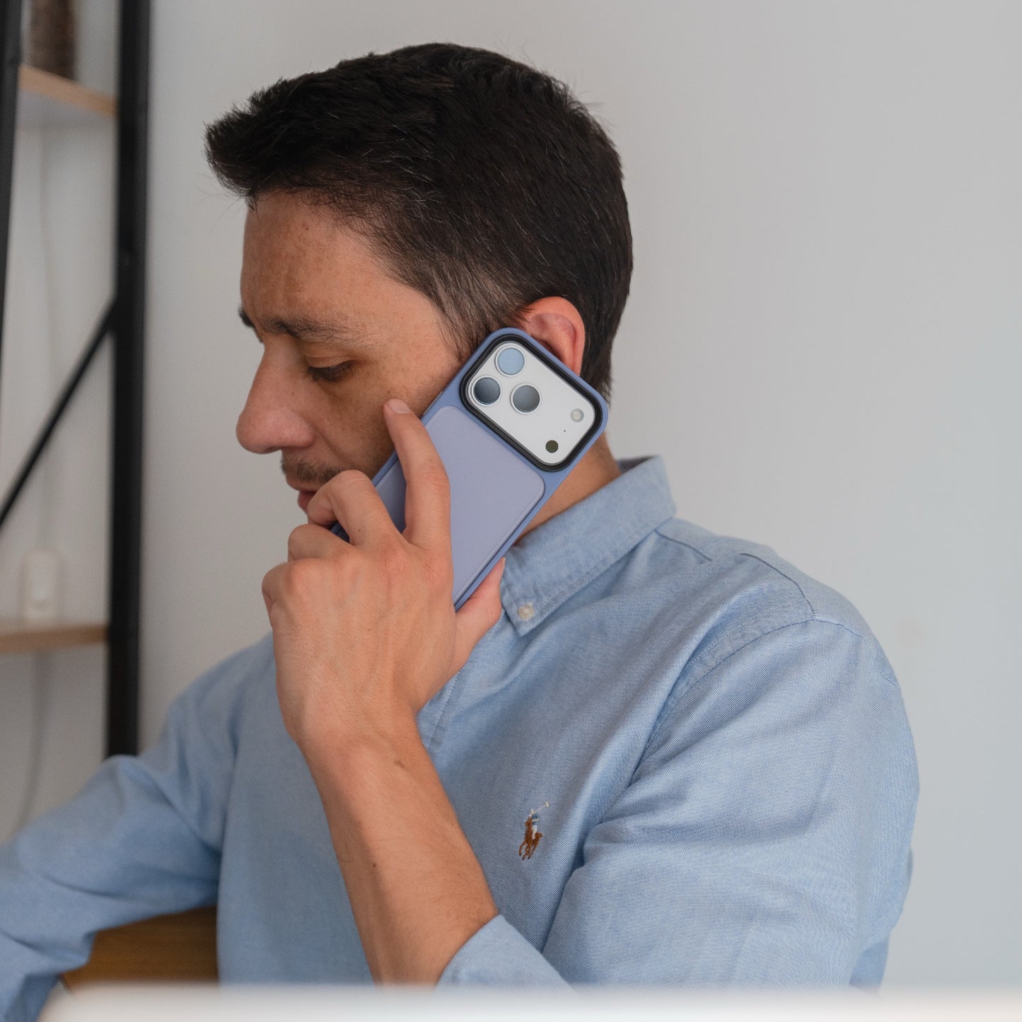Ein Mann in einem blauen Hemd hält sich zwei Smartphones ans Ohr und scheint mit beiden zu sprechen; ein Telefon wird durch das Arktis arktis iPhone 17 Pro Solid Case geschützt.