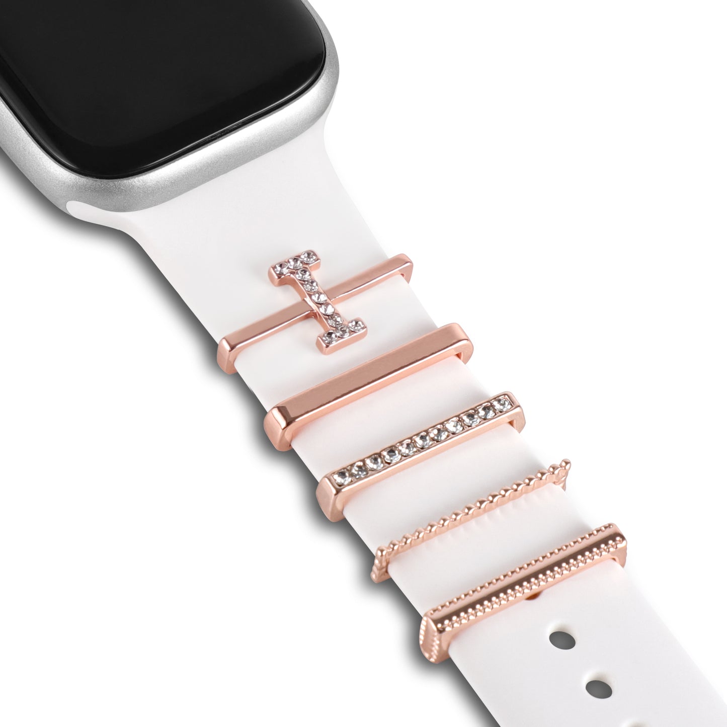 Nahaufnahme eines weißen Arktisband-Armbands für die Apple Watch, verziert mit fünf einzigartigen roségoldenen „I Style“-Anhängern, einer davon mit klaren Steinen. Das Arktisband und das teilweise sichtbare Zifferblatt sind oben links zu sehen.