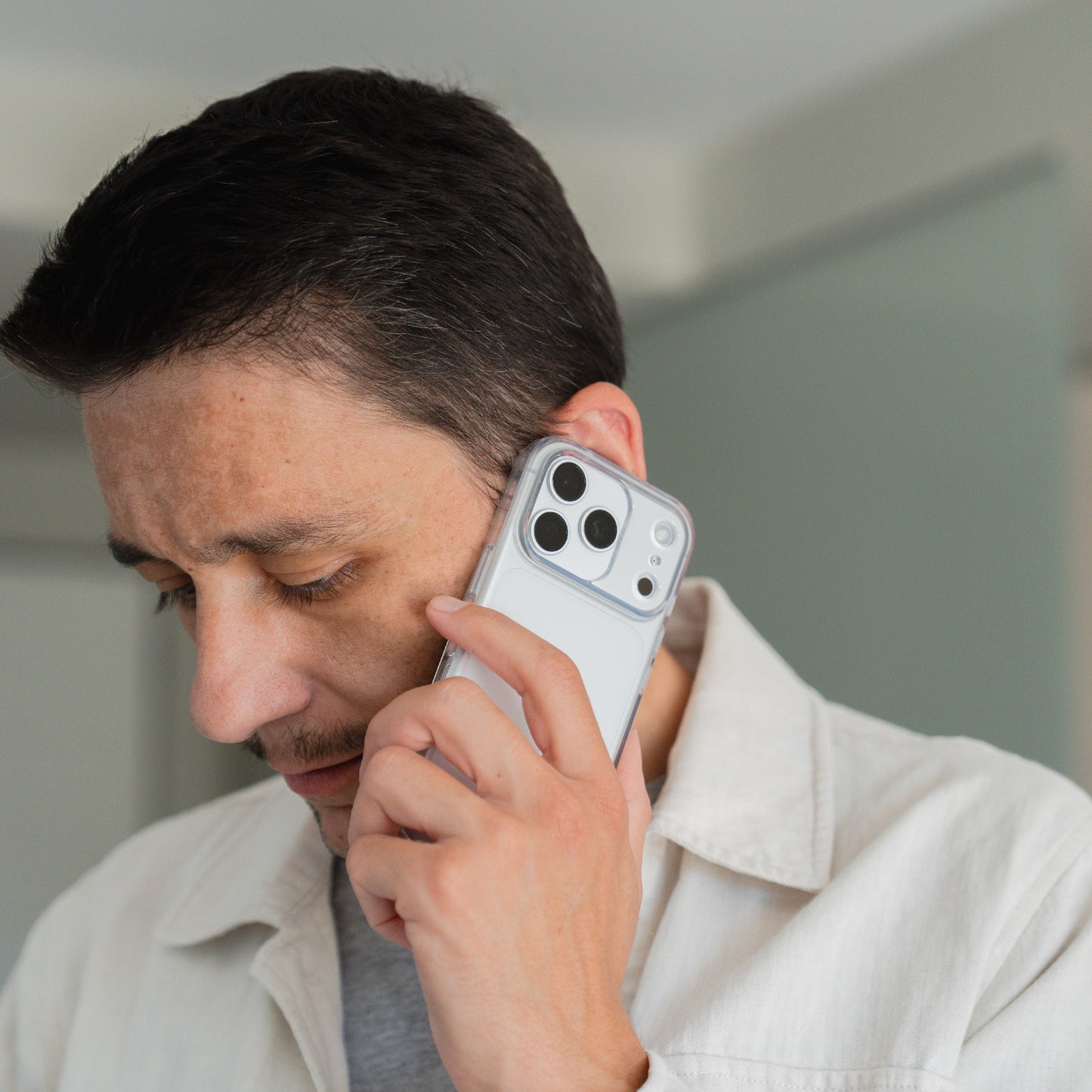 Ein Mann hält ein mit einer unsichtbaren Hülle versehenes iPhone 17 Pro Max von arktis an sein Ohr und unterhält sich konzentriert in einem Raum.