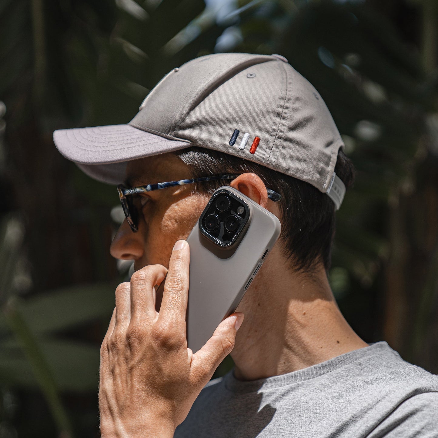 Mann mit grauer Mütze und Sonnenbrille hält im Freien ein iPhone 15 Plus mit einer MR PROTECT iPhone 15 Plus FROZEN-Hülle an sein Ohr.