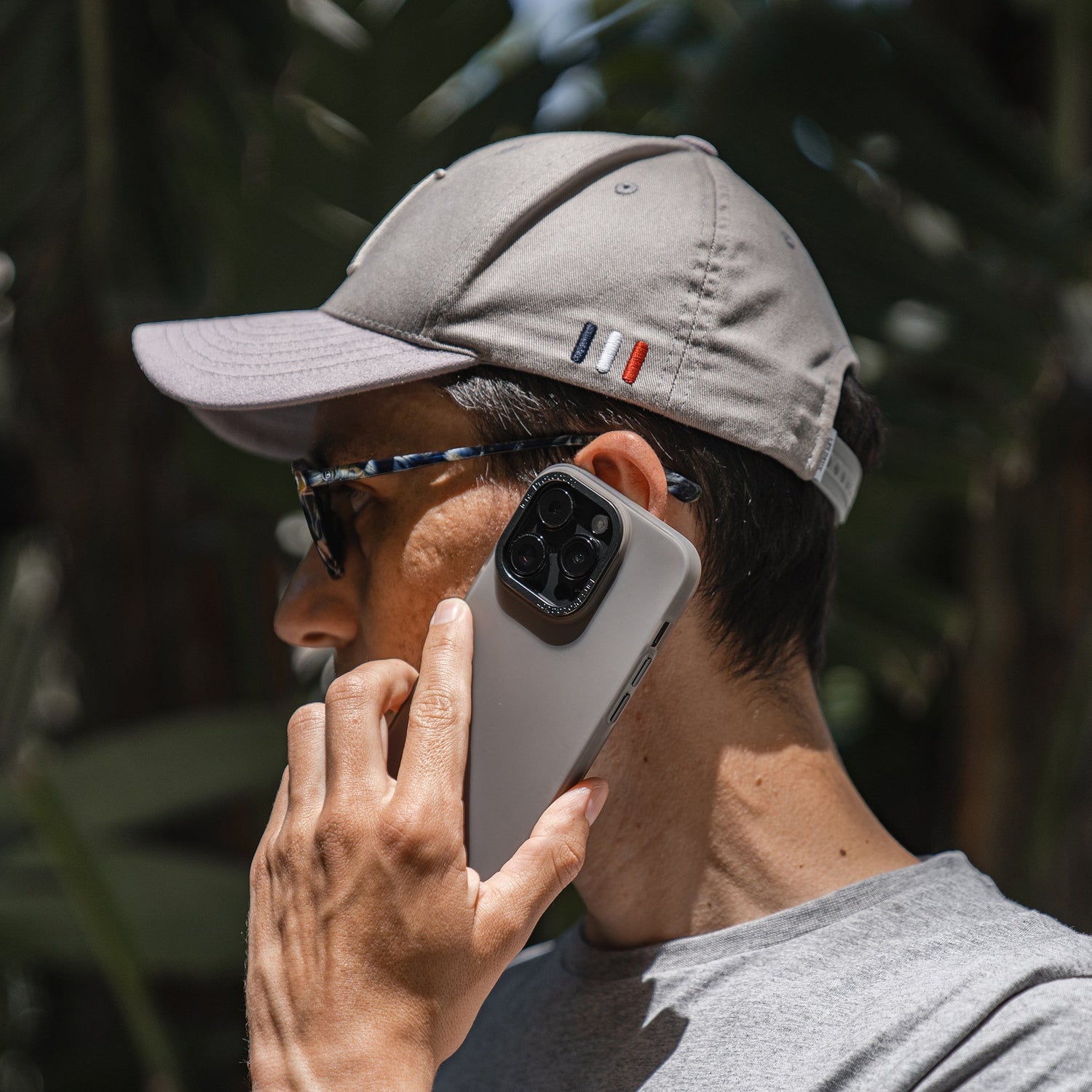 Mann mit grauer Mütze und Sonnenbrille hält im Freien ein iPhone 15 Plus mit einer MR PROTECT iPhone 15 Plus FROZEN-Hülle an sein Ohr.